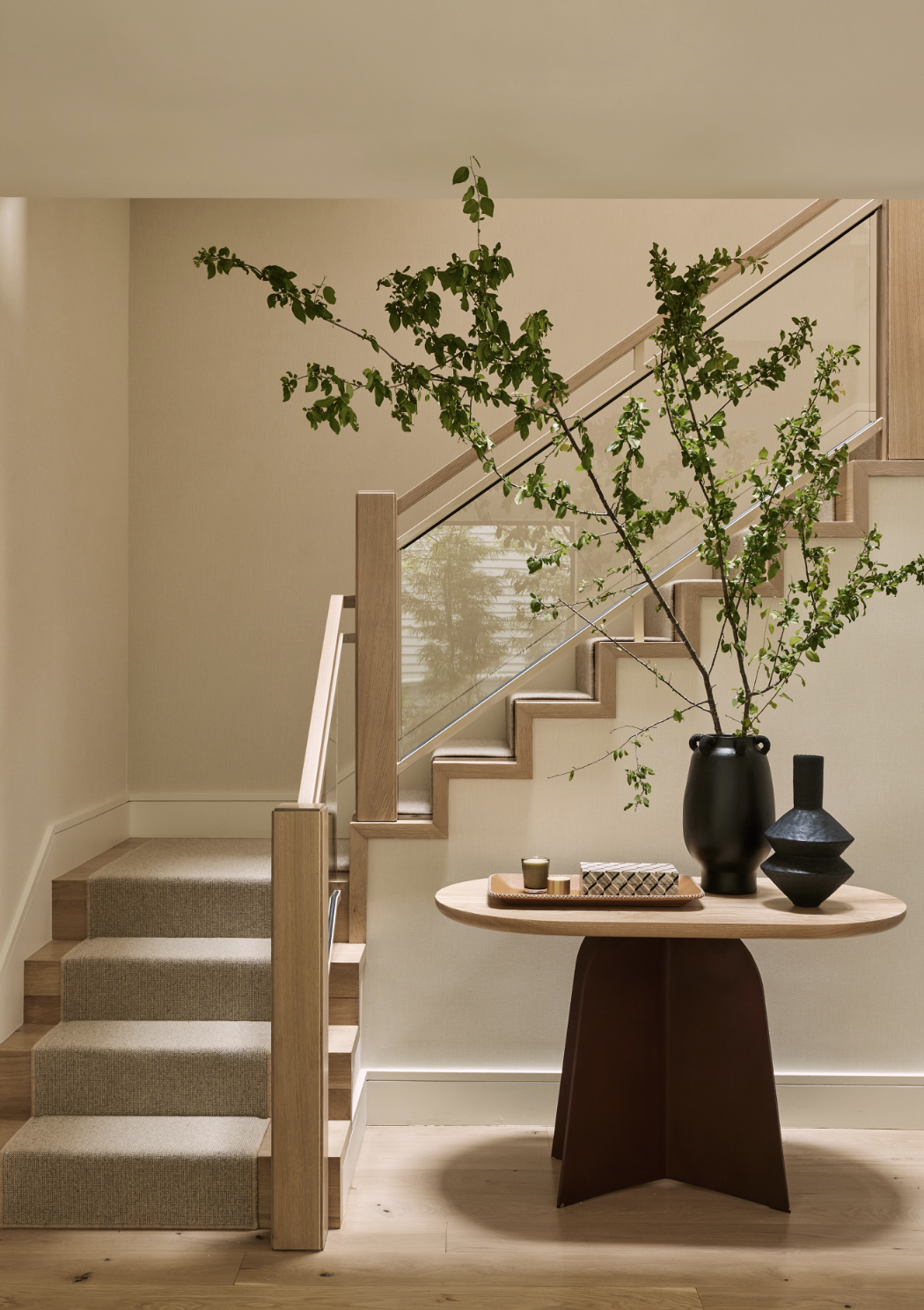 Union Street Marina District stair hall in San Francisco with a wood staircase and beige runner, styled with a wood table, sculptural black vases, leafy branches, and candles for modern luxury residential interior design.