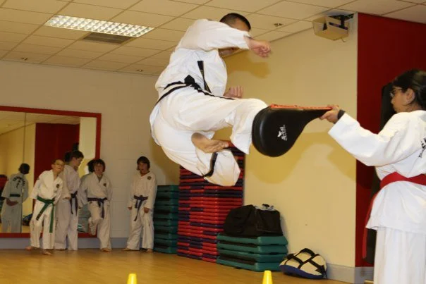 Martial arts class with students practicing punches and kicks in a dojo.