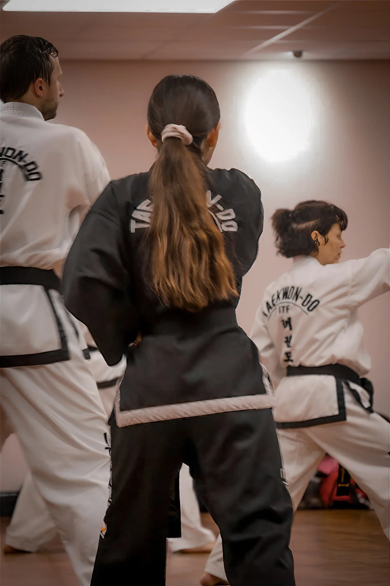 People practicing martial arts in a dojo, wearing traditional uniforms and belts.