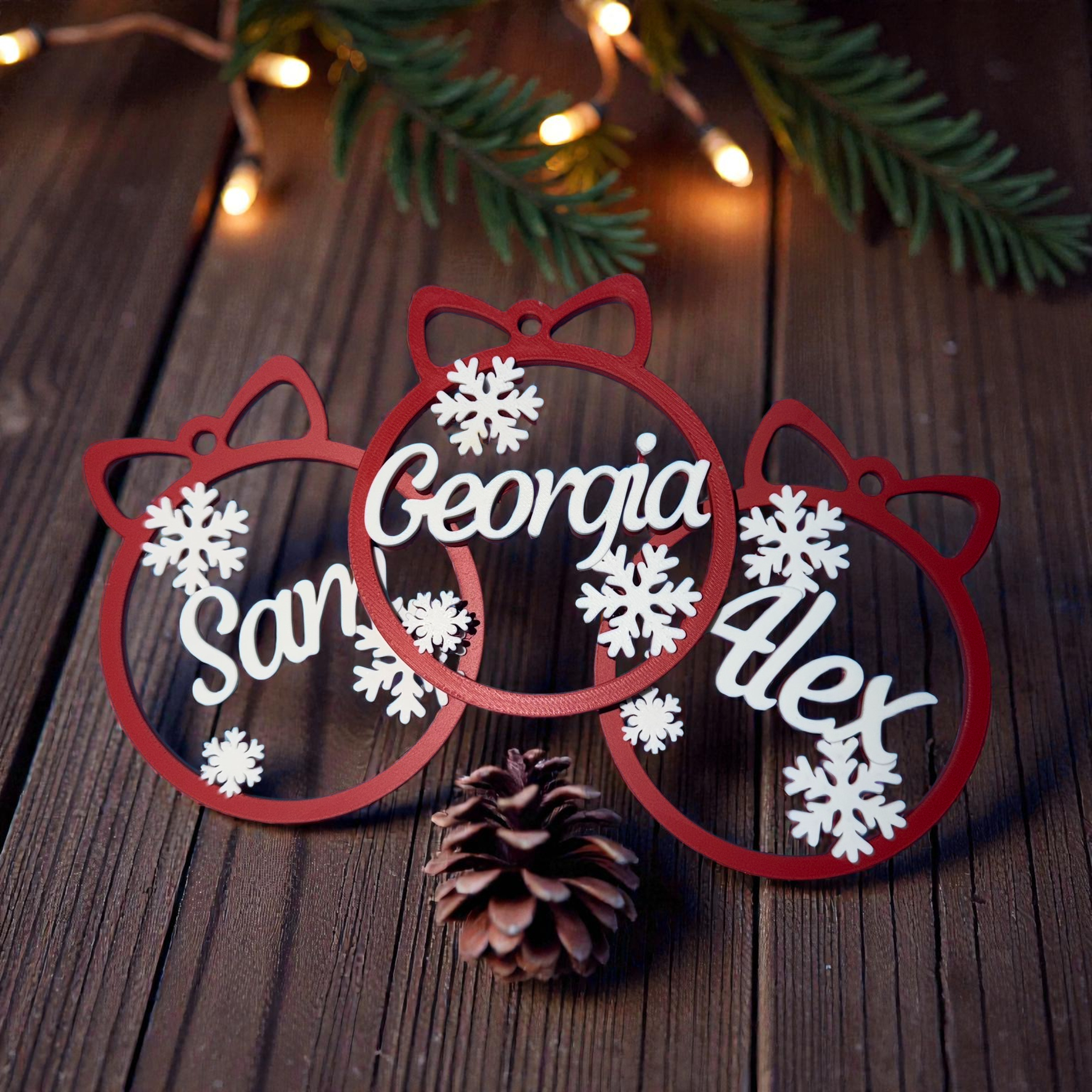 Three red baubles with white custom names across the middle