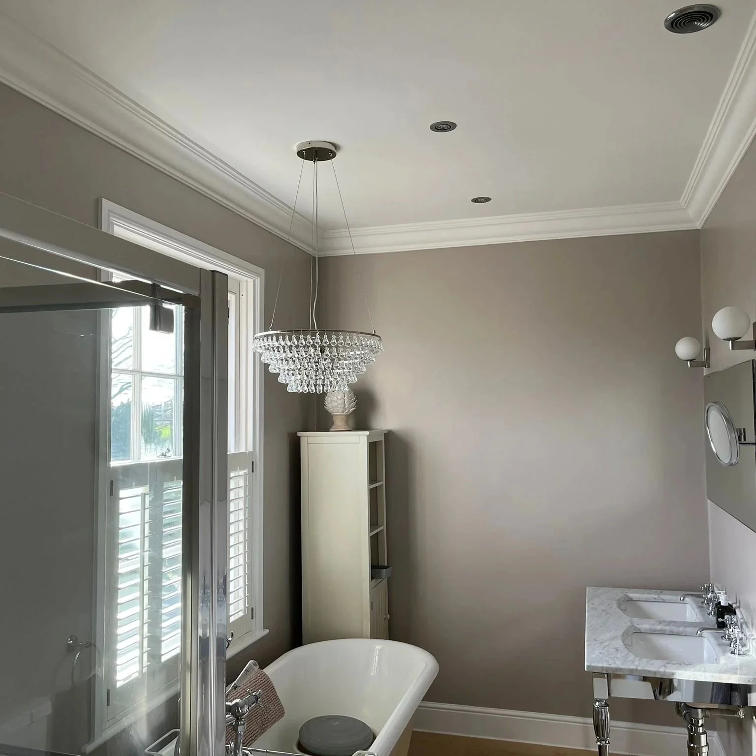 Elegant bathroom with a chandelier, clawfoot bathtub, double sink vanity, and neutral wall colors.
