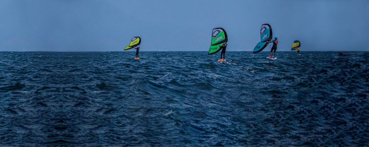 Four kitesurfers gliding across the ocean with colorful sails.