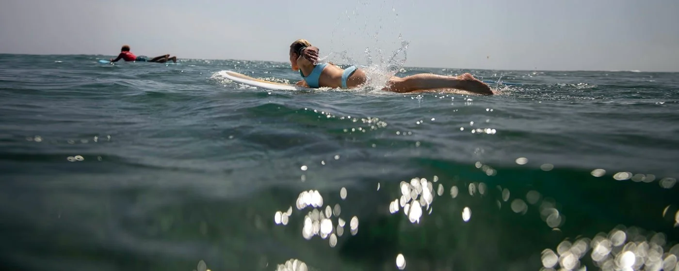 A woman in a blue swimsuit surfing on a wave in the ocean.