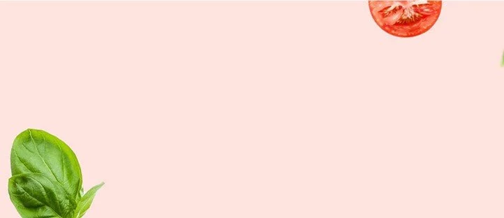 Partial view of tomato slice and basil leaves on a pink background.