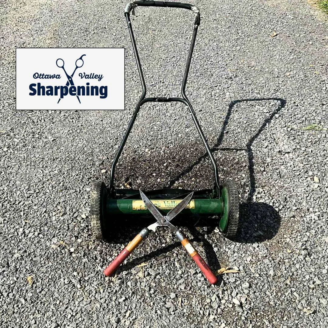 A lawn mower with hedge trimmers crossed on top of it, on a gravel surface. Logo in the top left corner says 'Ottawa Valley Sharpening'.