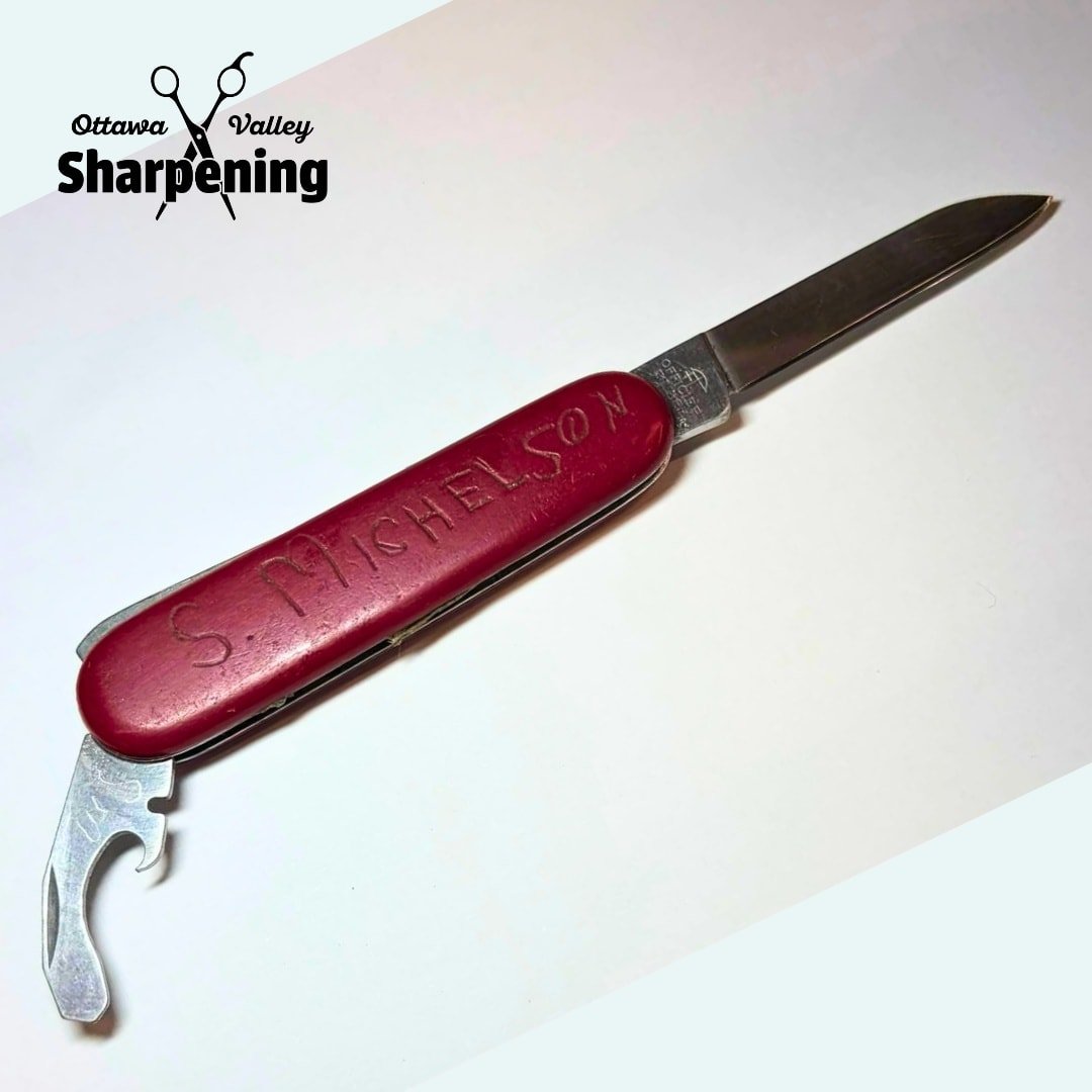 A Swiss Army knife with a red handle engraved with 'S. Tichenor' and a partially extended metal blade, placed on a white surface with a 'Ottawa Valley Sharpening' logo in the top left corner.