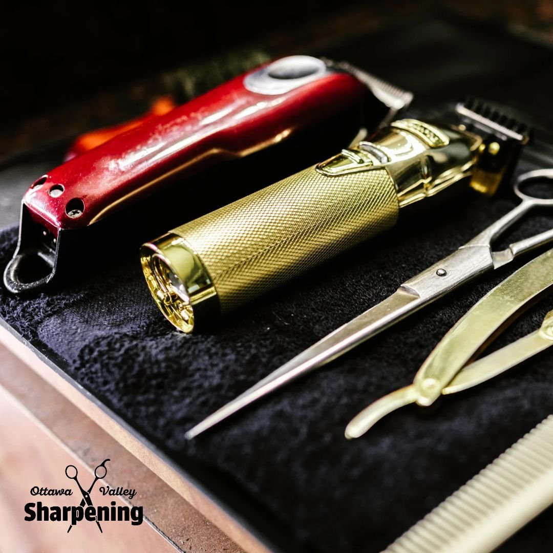 Close-up of grooming tools including a red electric clipper, a gold manual trimmer, a pair of scissors, a pair of nail clippers, and a comb, arranged on a black surface. Ottawa Valley Sharpening logo is in the lower left corner.