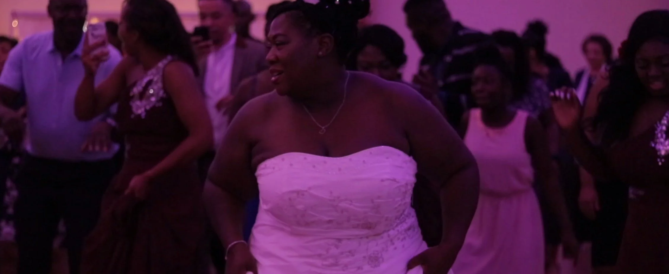People dancing at a celebration event under purple lighting.