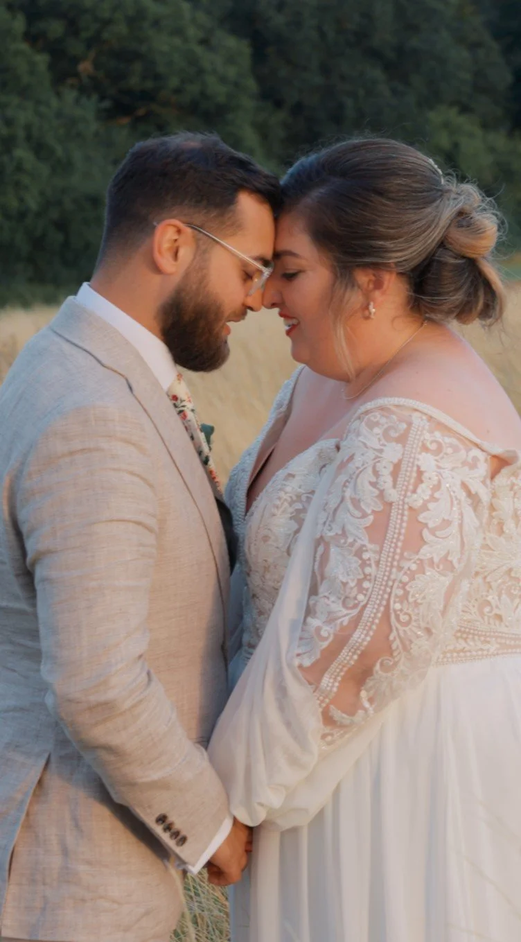 Bride and groom standing close together outdoors, sharing a quiet moment on their wedding day.