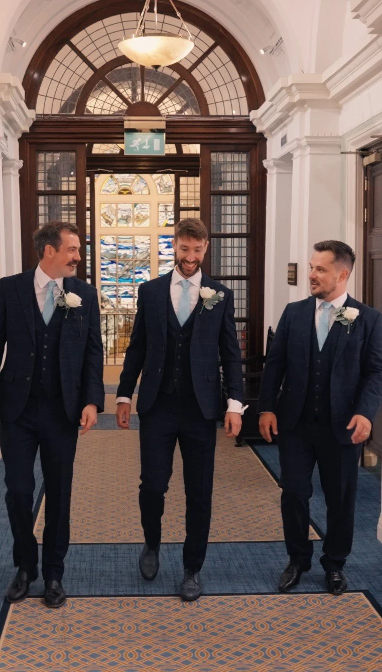 Groomsmen walking together inside a wedding venue, captured naturally before the ceremony.