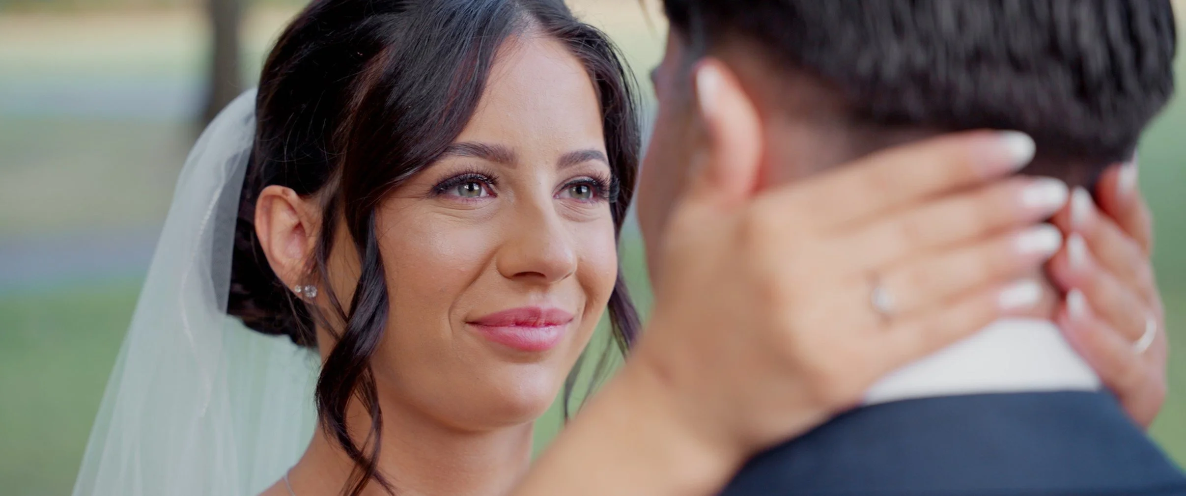 A bride and groom sharing an intimate moment, the bride gently holding the groom's face, smiling with her eyes.