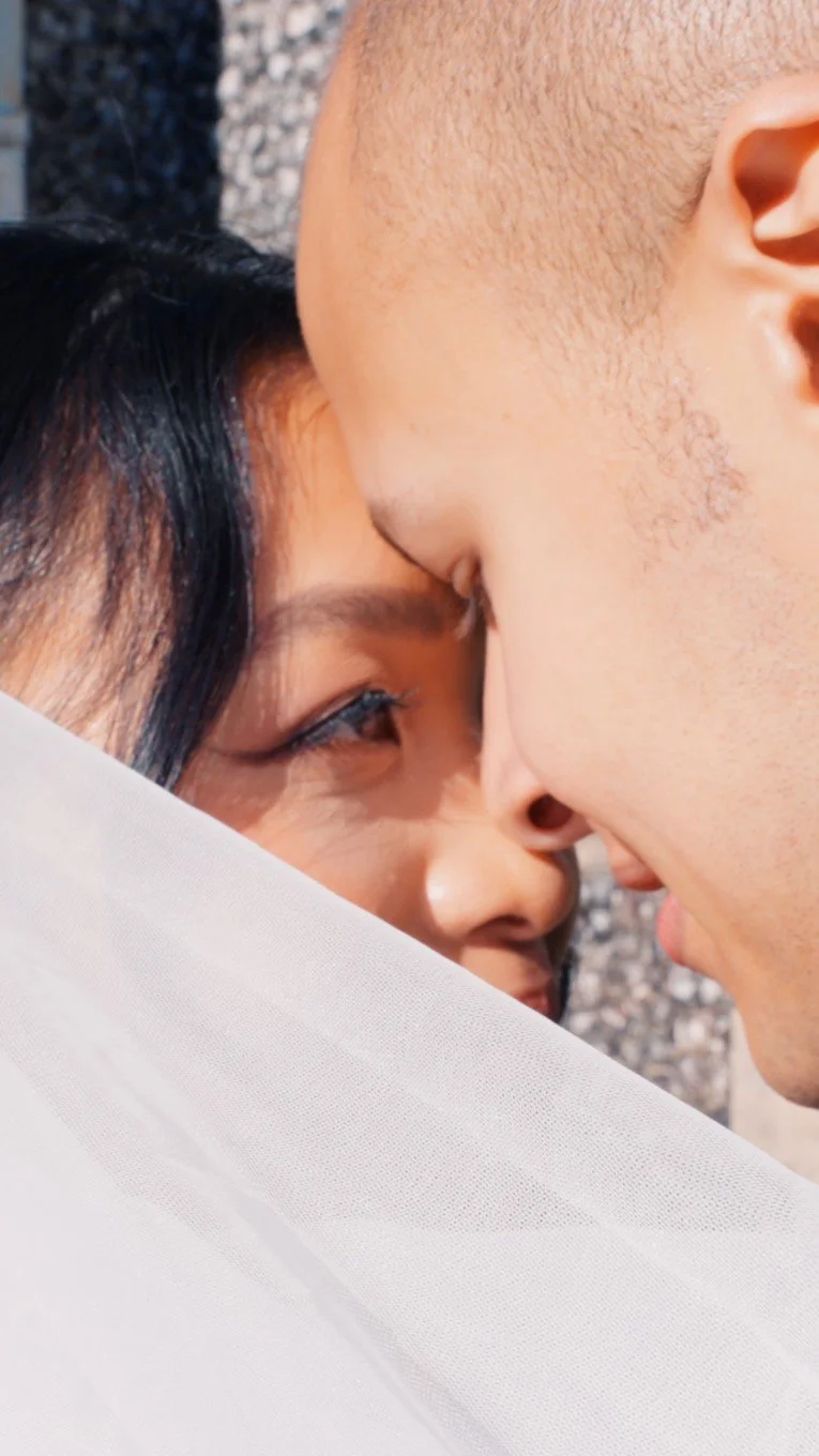 Close-up of bride and groom touching foreheads and smiling together on their wedding day.