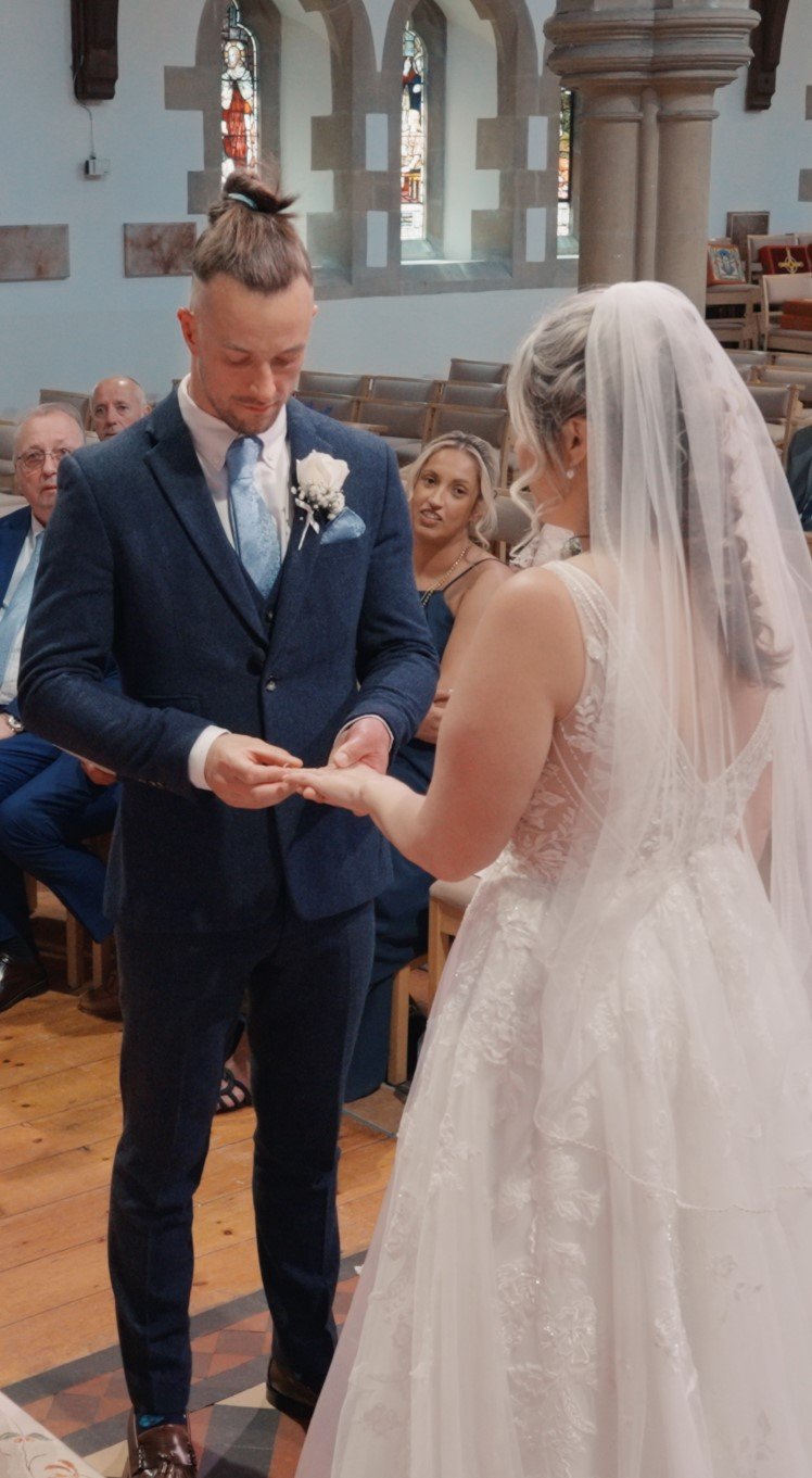 Bride and groom exchanging rings during their wedding ceremony inside a church.