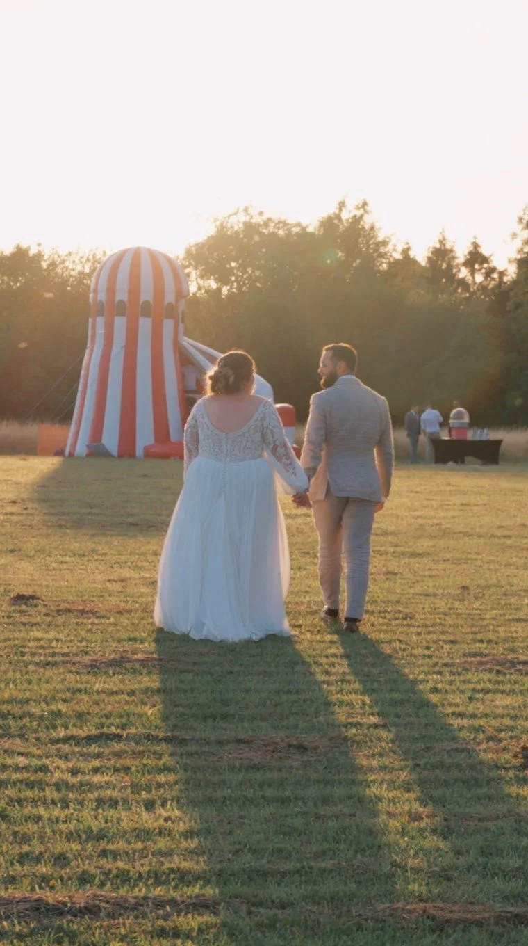 Bride and groom walking hand in hand at sunset during their wedding celebration.