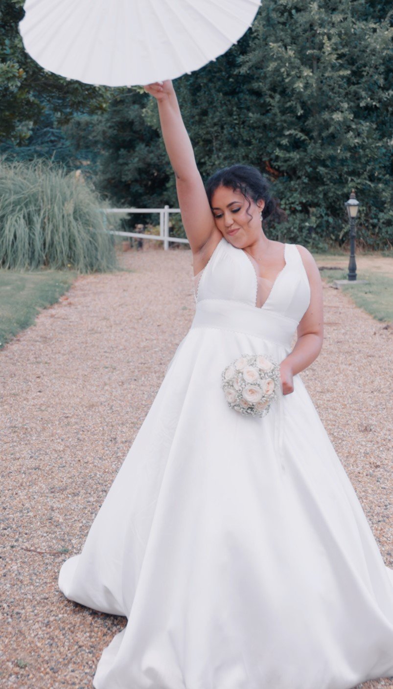 Bride standing outdoors holding her bouquet on her wedding day, captured in a relaxed portrait.