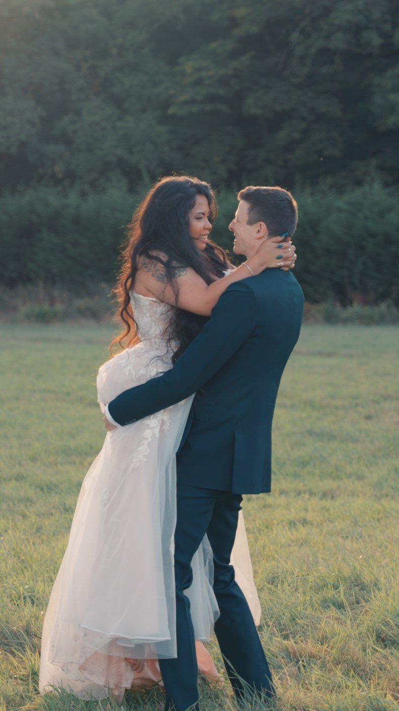 Bride and groom embracing outdoors on their wedding day, captured in a relaxed, natural style.