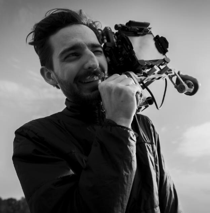 Man met een drone op zijn schouder, glimlachend, in een zwart-wit foto.