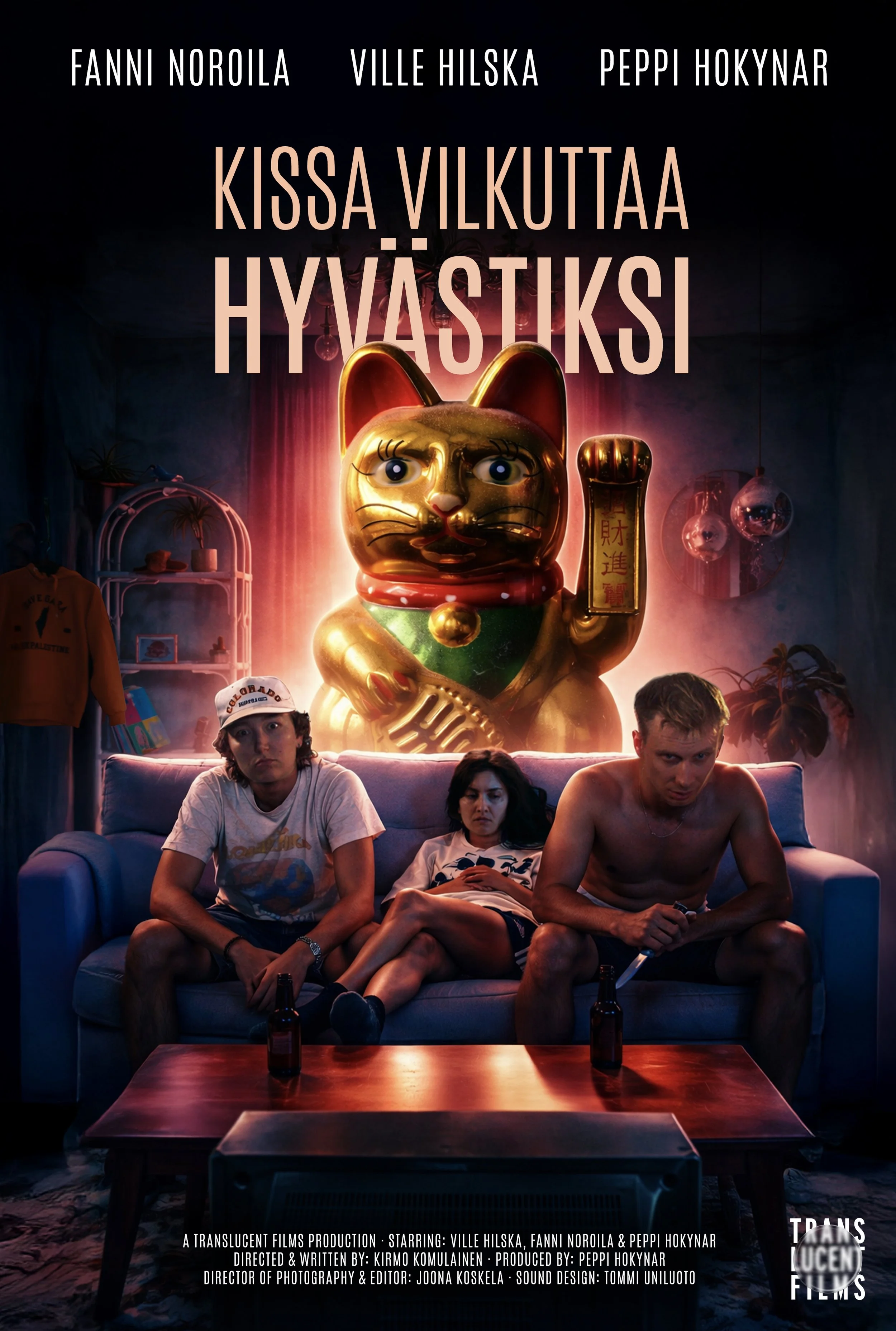 Leffajuliste, jossa kolme ihmistä istuu sohvalla; vasemmalla transmaskuliini henkilö, keskellä nainen ja oikealla mies, edessään pöytä ja pulloja. Takana suuri kultainen maneki-neko kissa ja hylly ja seinäkalusteita.