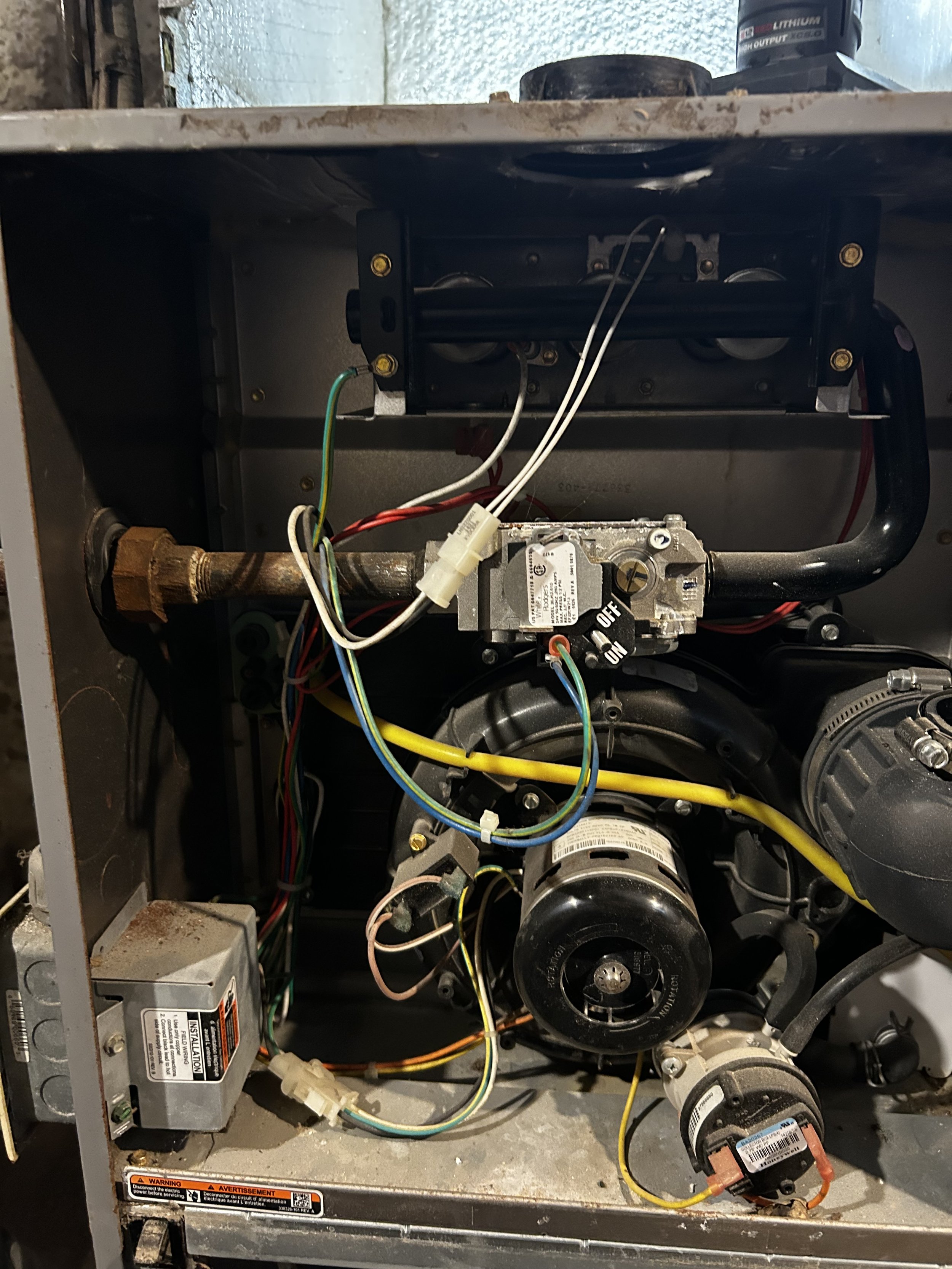 Inside view of an HVAC unit showing various electrical components, wiring, and a motor with a black pulley.