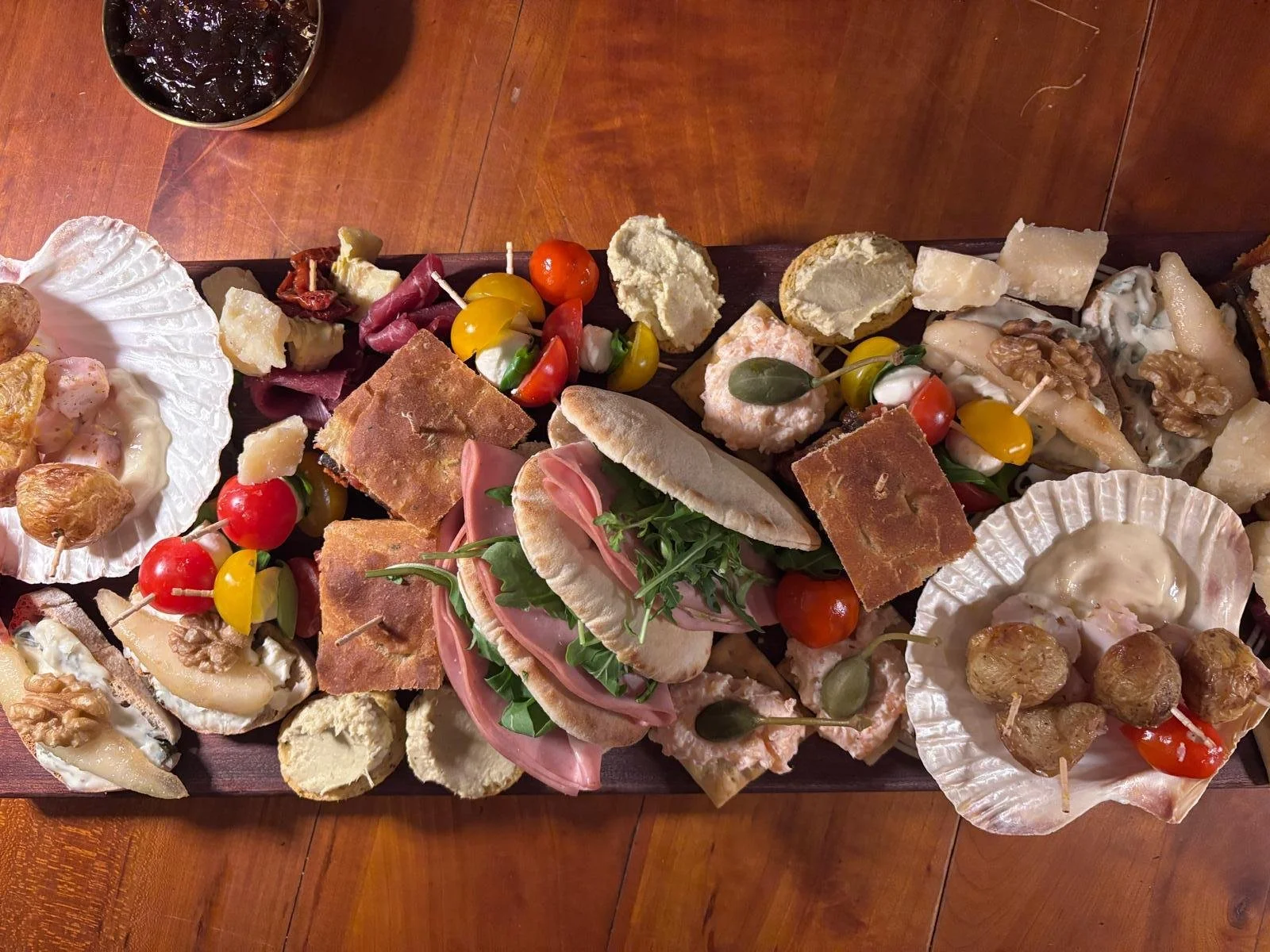 Assorted cheeses, crackers, cherry tomatoes, green grapes, nuts, and other appetizers on a serving platter.