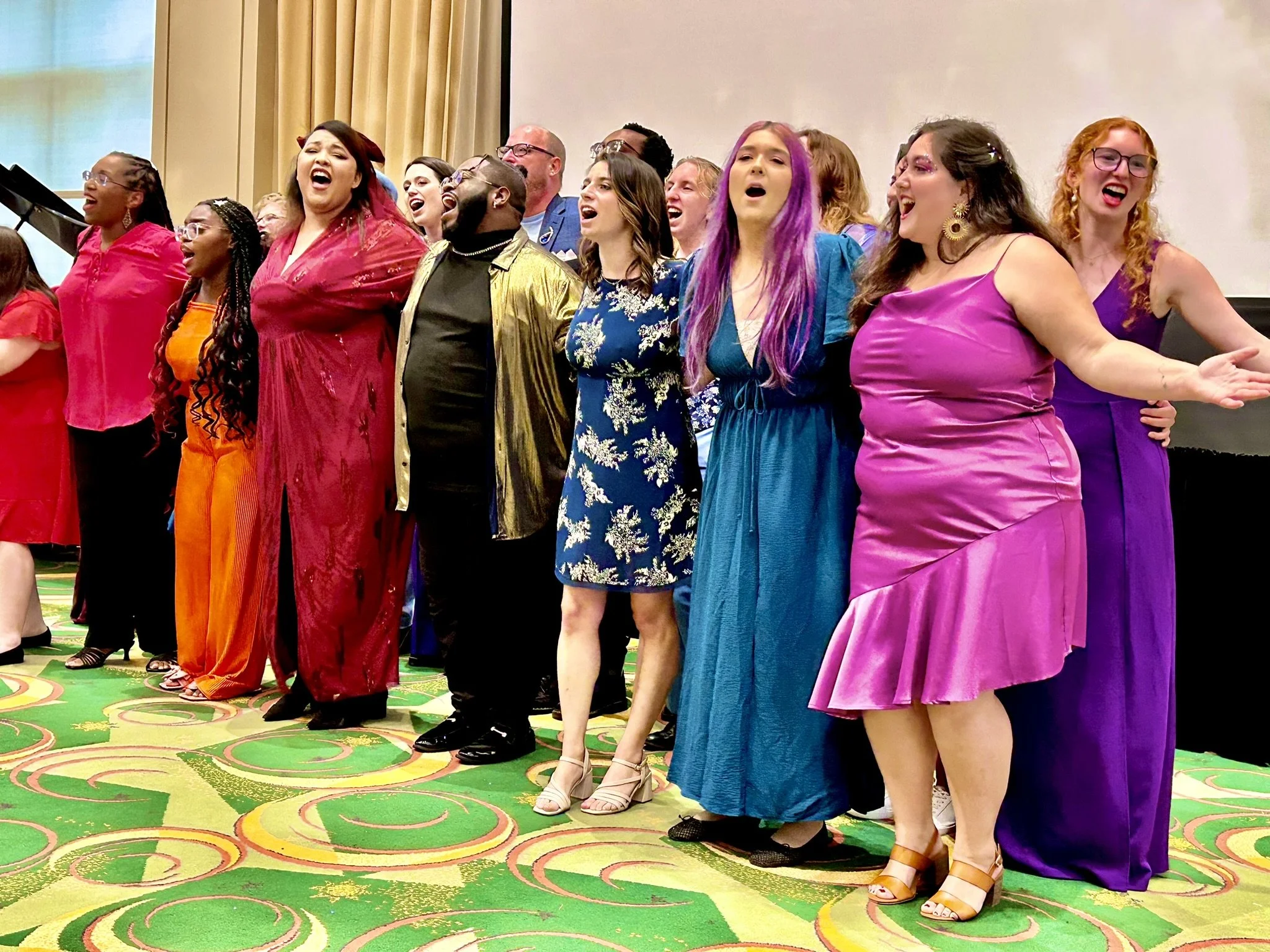 Group of people singing with their eyes closed and arms outstretched in a colorful indoor setting.