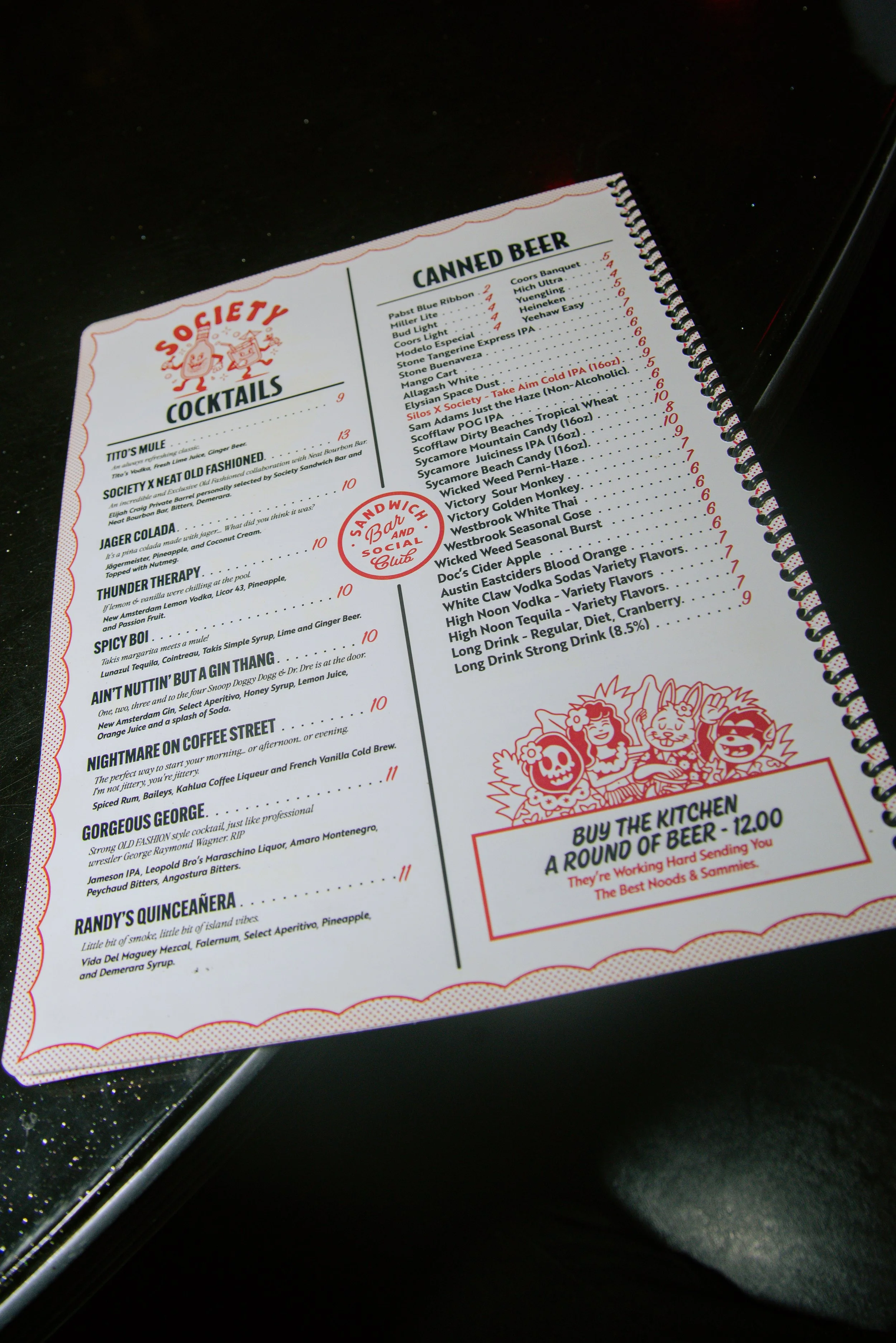 Close-up of a menu page with a section titled 'CANNED BEER' listing various brands and prices, and a section for cocktails and social drinks at a bar or restaurant.