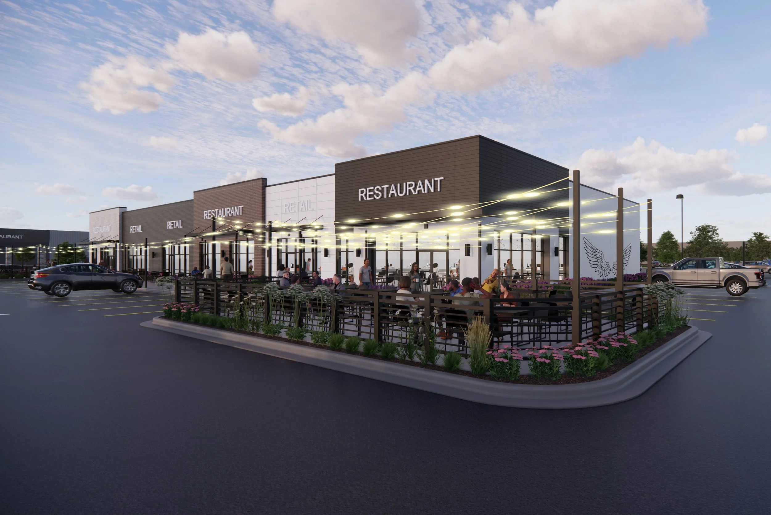 A modern shopping plaza with a restaurant and retail stores, outdoor seating area with people dining, parking lot with cars, and a partly cloudy sky.