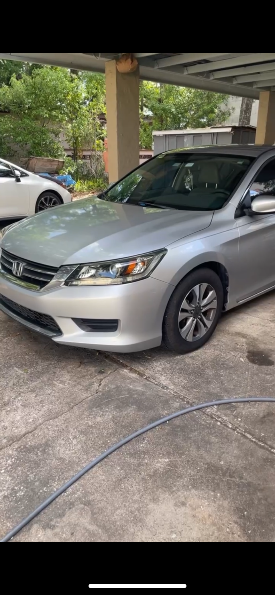 A silver Honda sedan parked under a carport with another white car parked nearby.