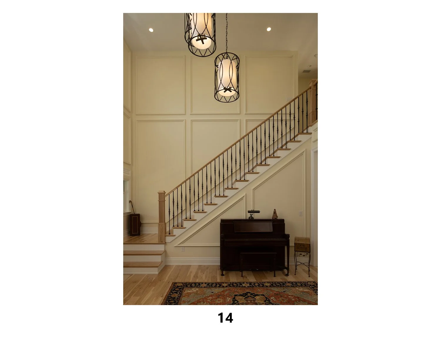 Interior view of a staircase with a vaulted ceiling, modern light fixtures, a piano, and a decorative rug.