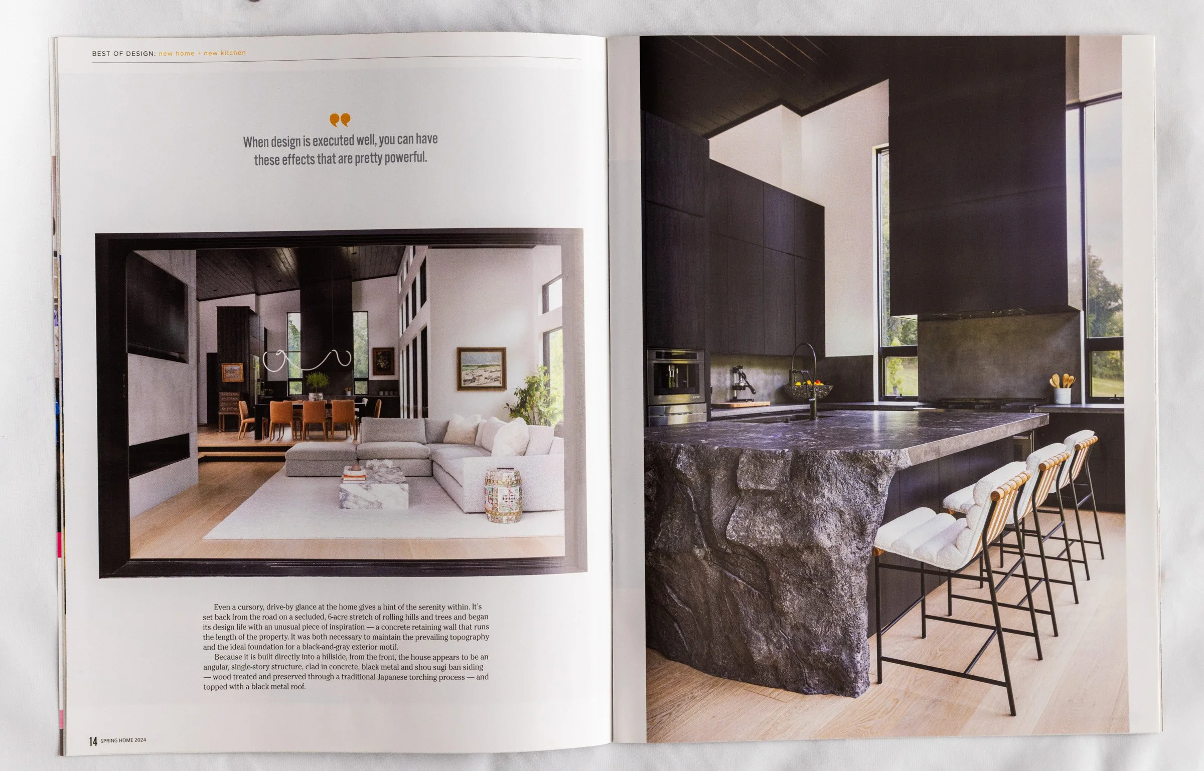Open magazine showing images of modern living room and kitchen with dark cabinetry and large windows.