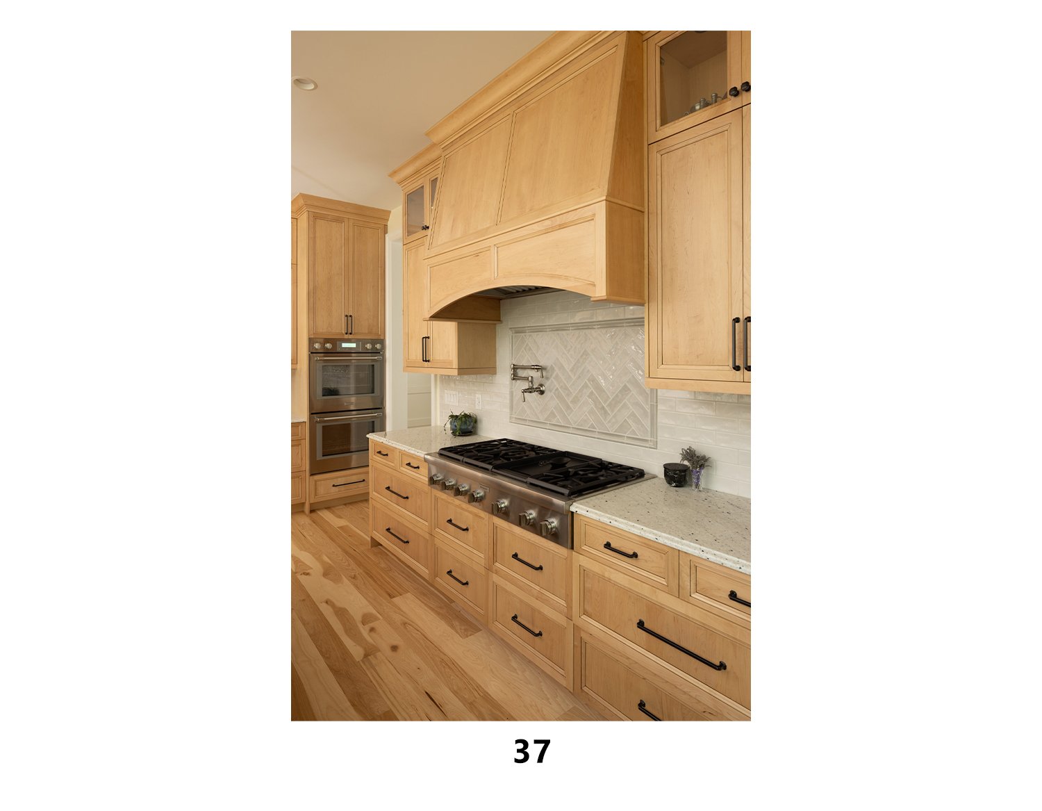 Kitchen with light wood cabinets, a gas stove, a built-in oven, and a decorative backsplash with a faucet. Small decorative items are on the countertop.