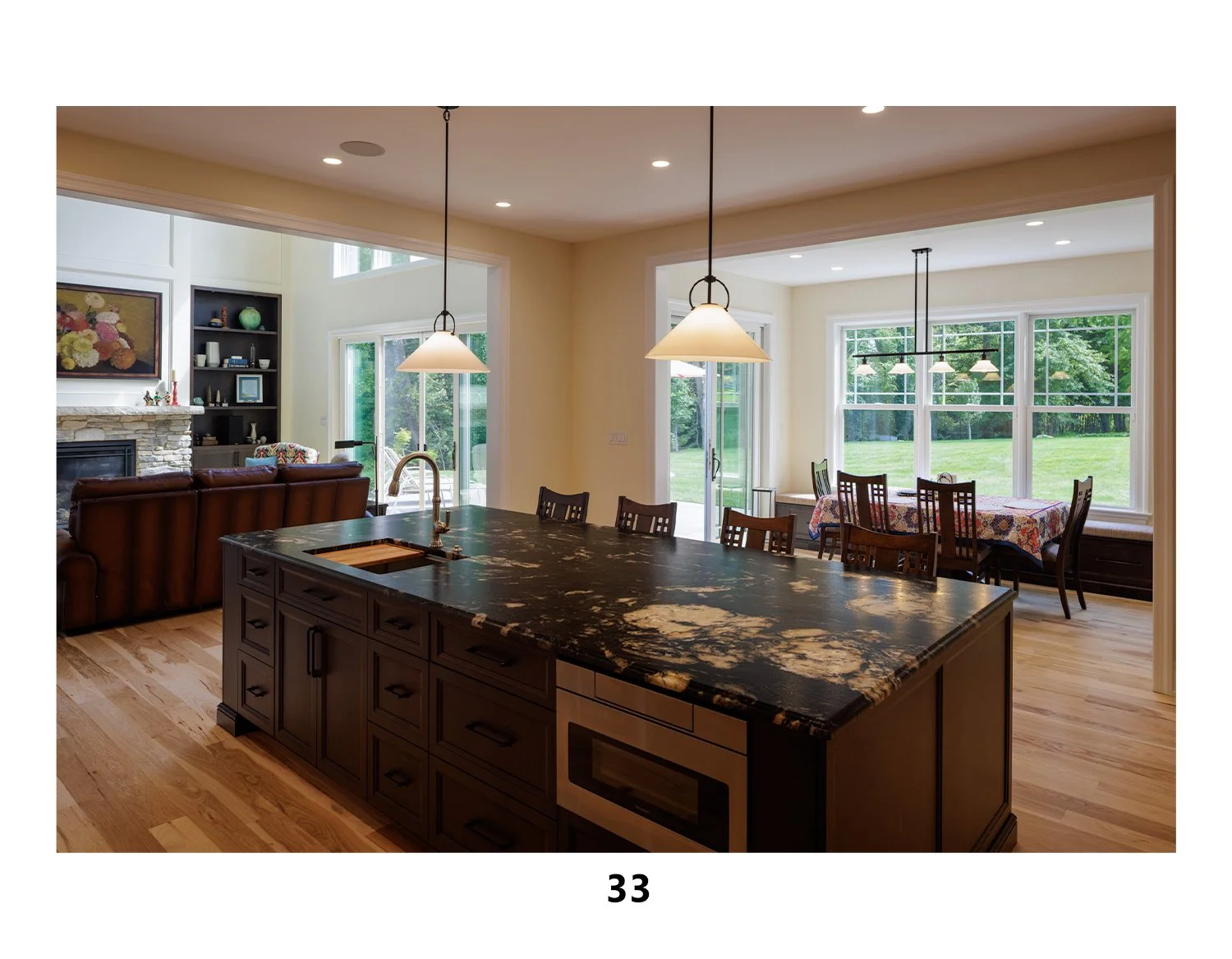 Open-concept kitchen and dining area with large windows, wooden flooring, and modern lighting fixtures.