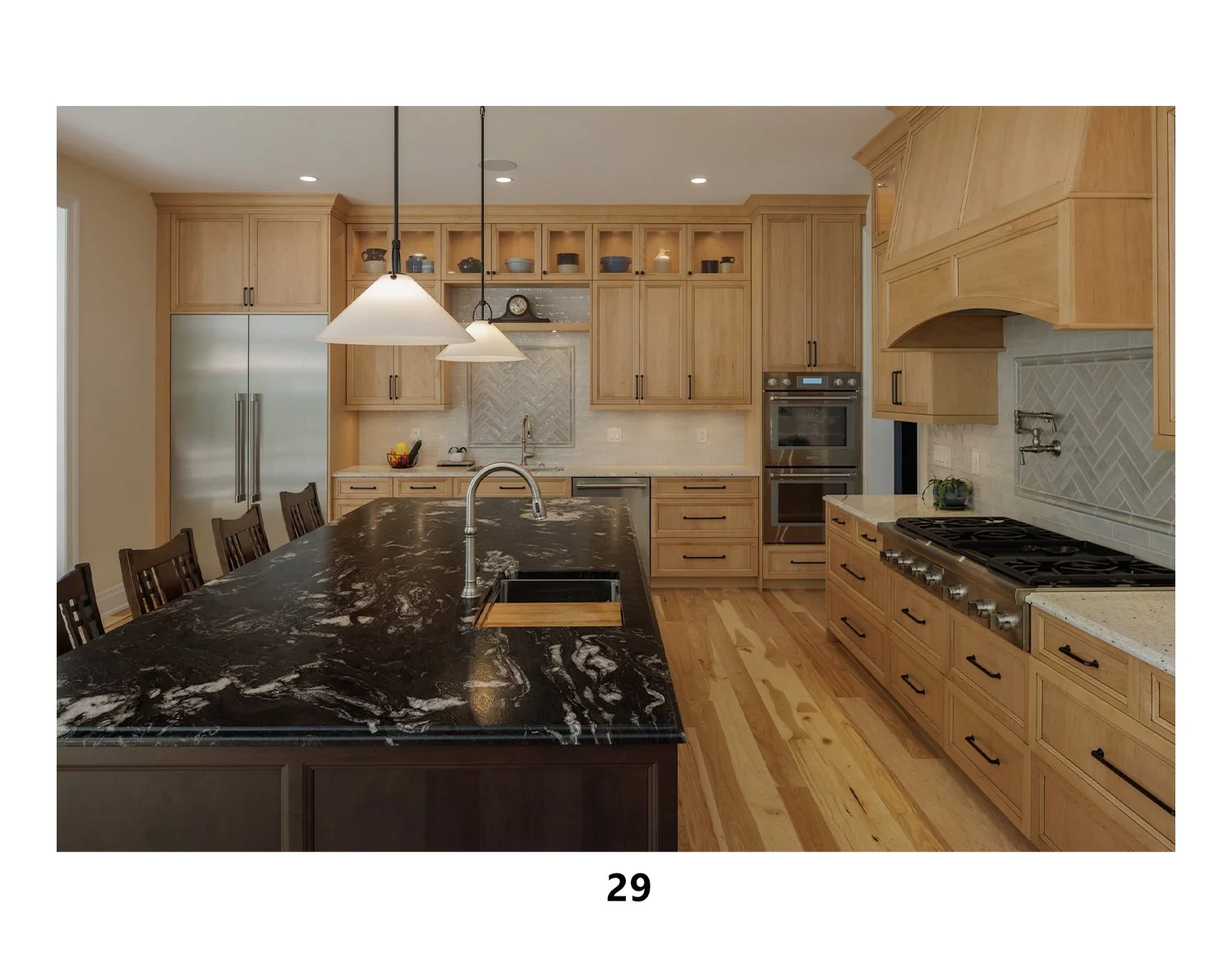 Kitchen with light wood cabinets, a large black marble island with a sink, and stainless steel appliances including a refrigerator and oven. Pendant lights hang above the island. Hardwood floors are visible.