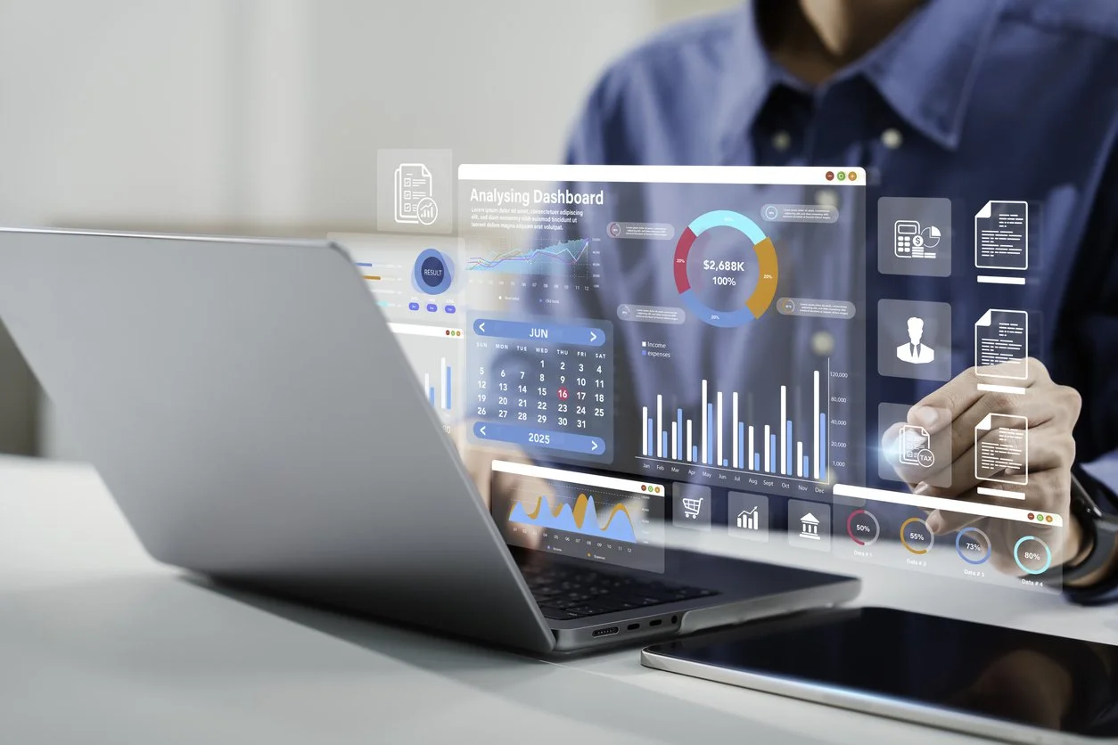 A person using a laptop with a transparent digital dashboard displaying various charts, graphs, and icons related to data analysis and business metrics.