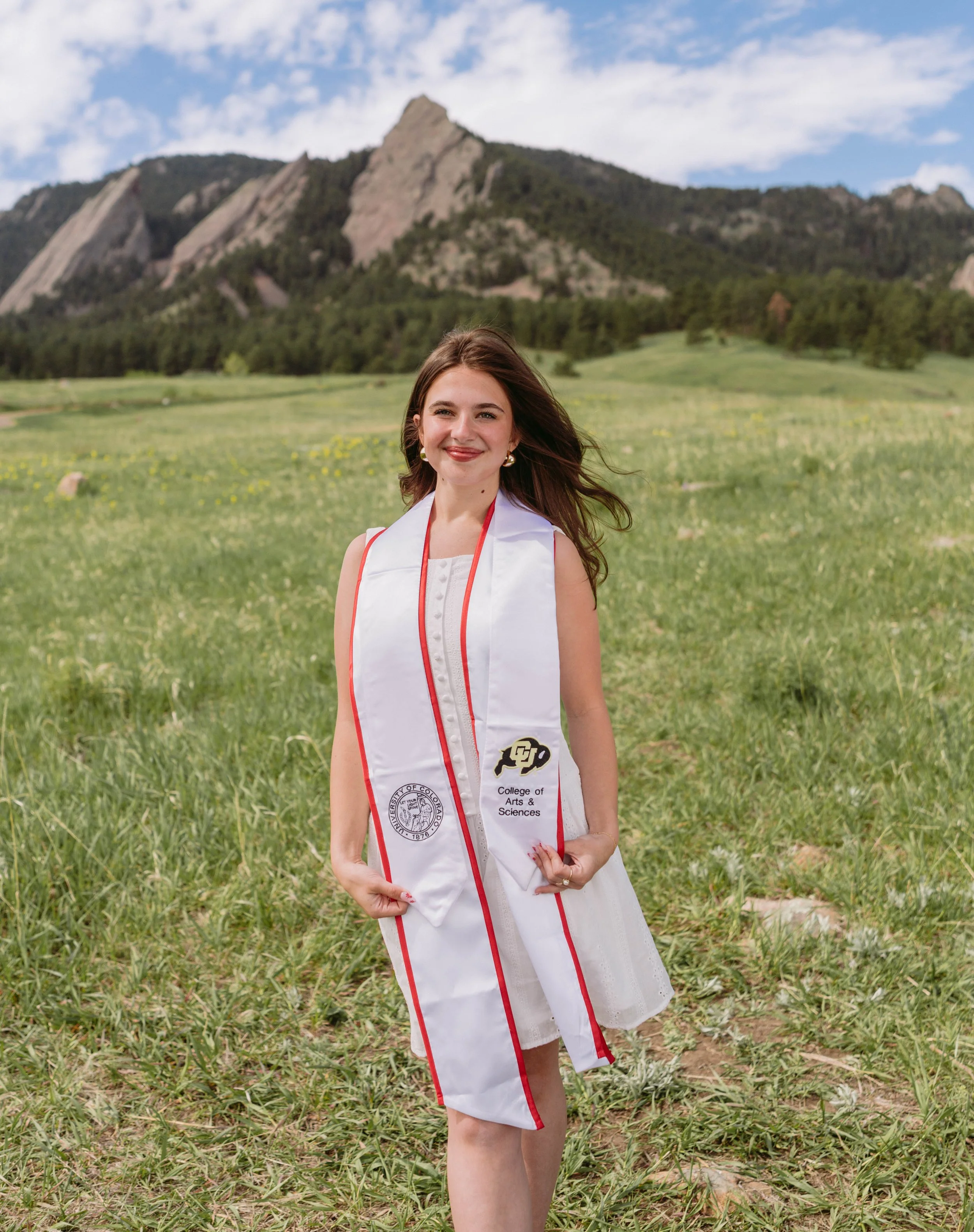 Brunette female graduate in front of the flatirons in Boulder Colorado