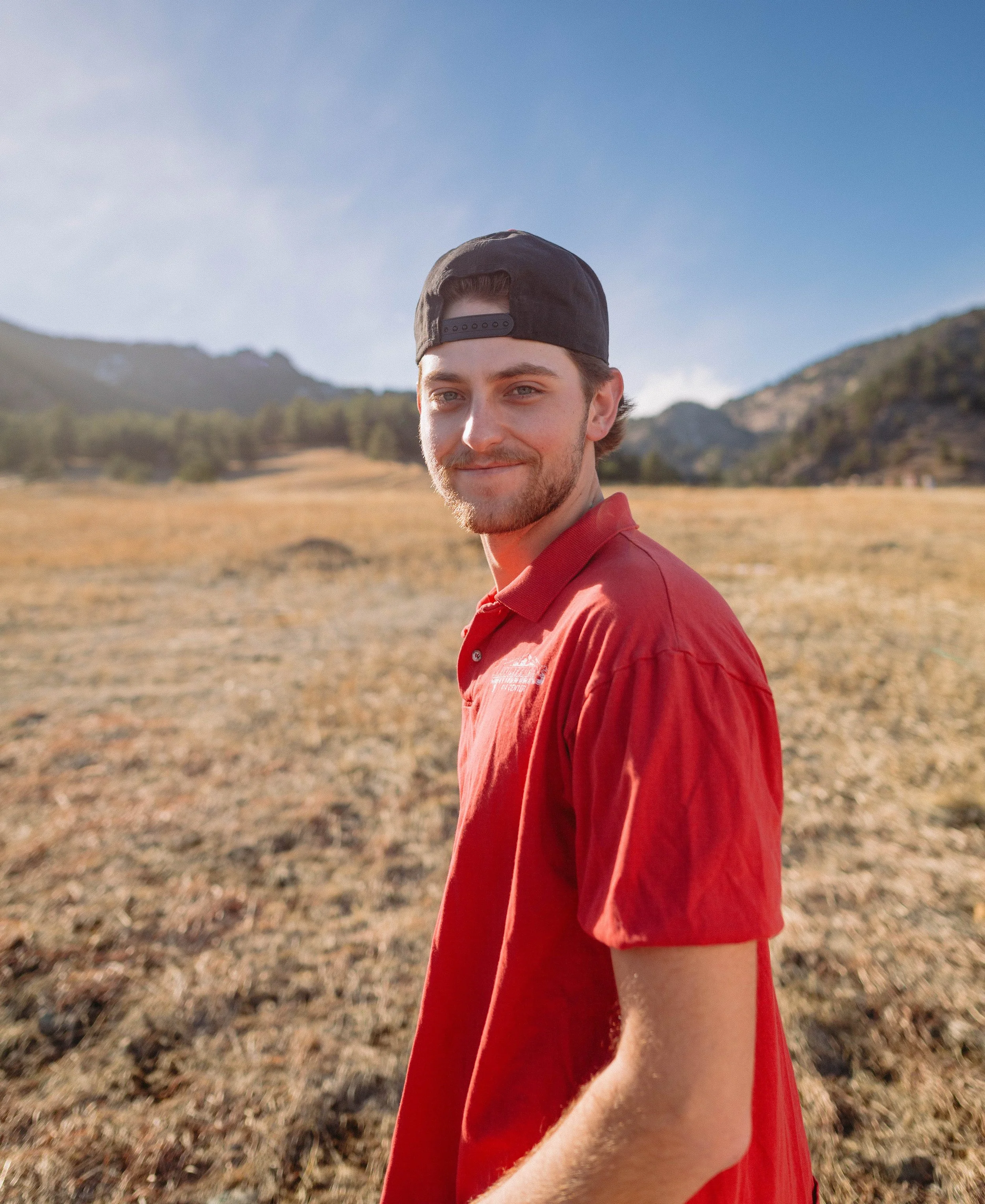 CU Boulder senior portrait of male graduate outdoors with mountain backdrop