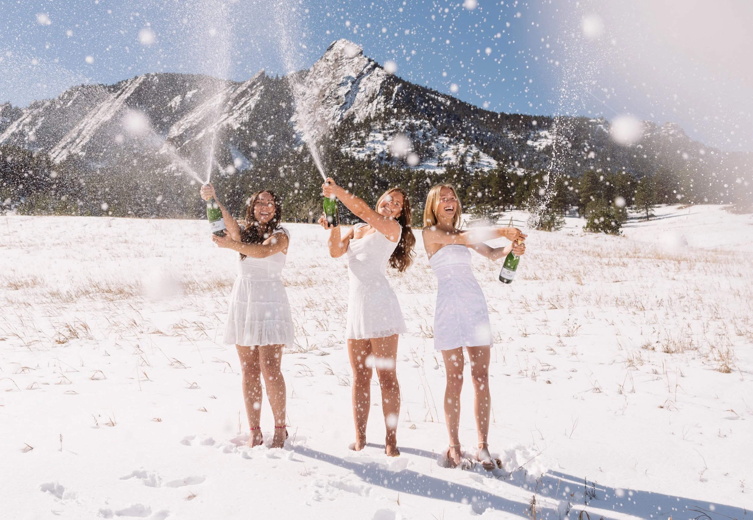 Group of CU Boulder seniors celebrating graduation with champagne spray in snowy field