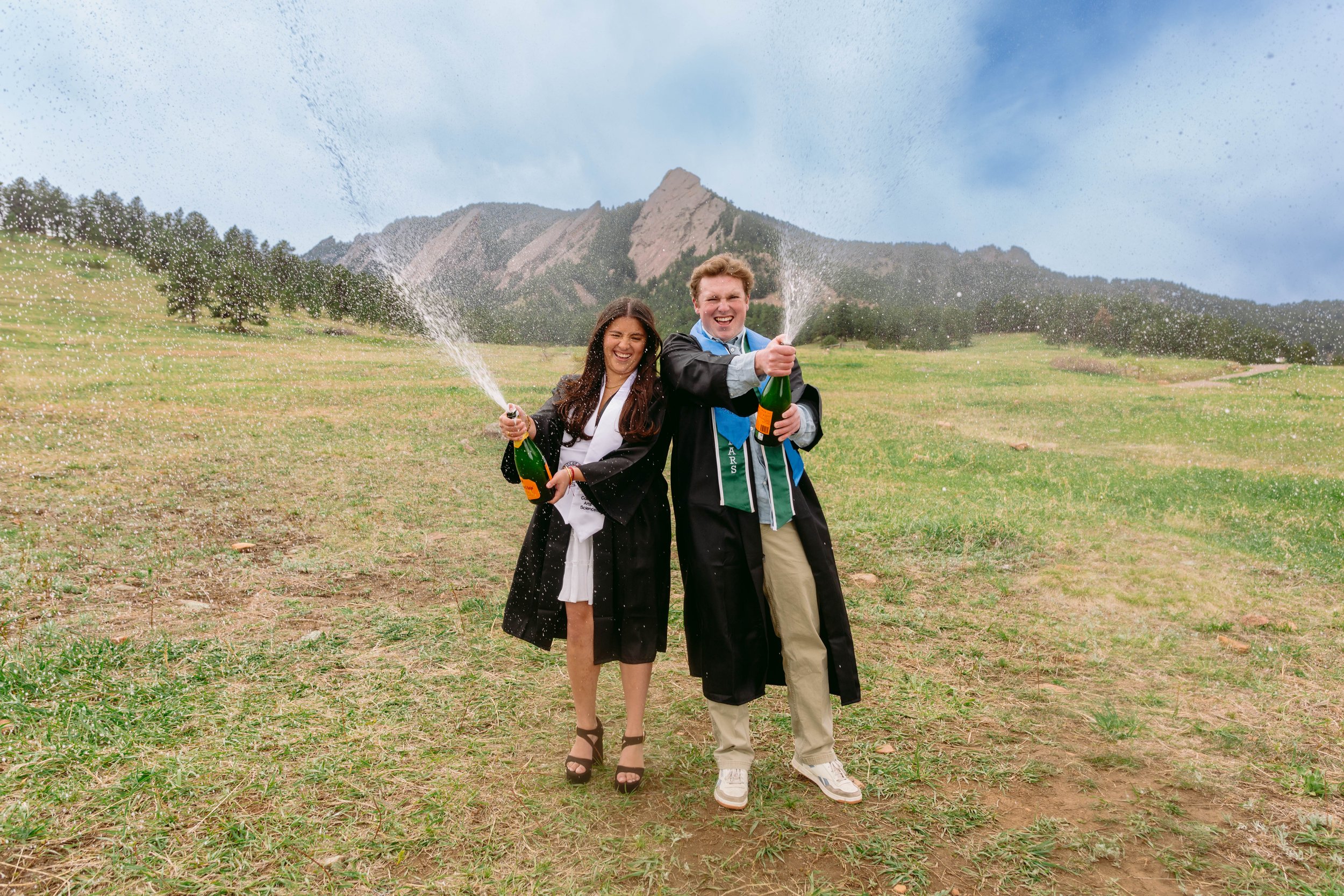 CU Boulder seniors celebrating graduation with champagne in open field