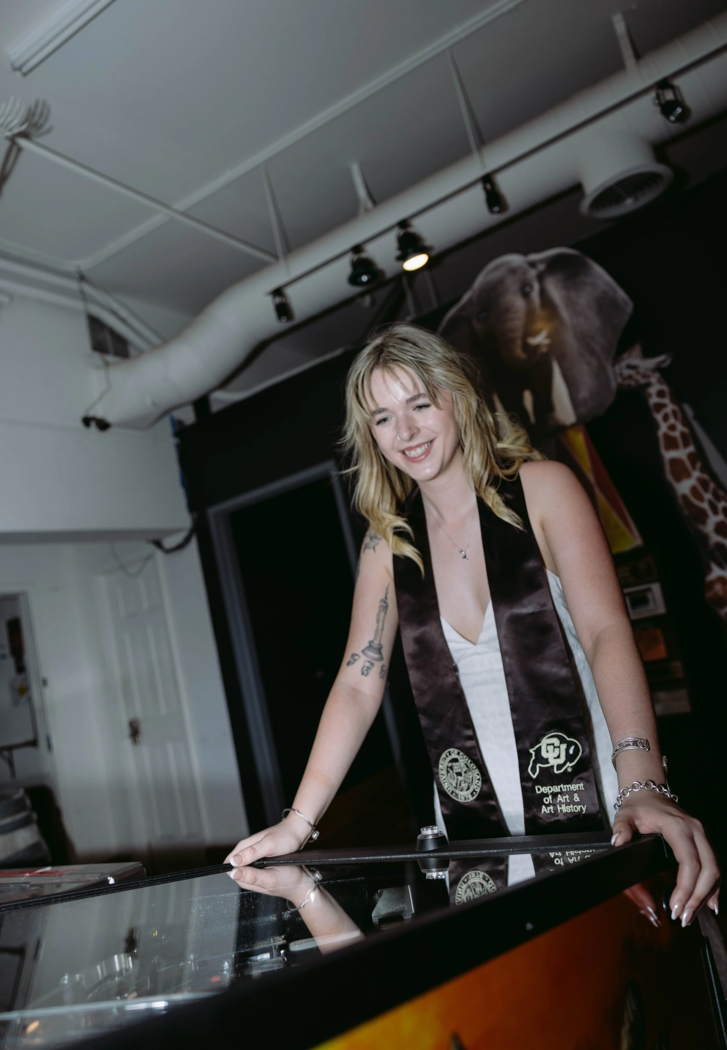 CU Boulder senior portrait indoors wearing graduation stole and white dress