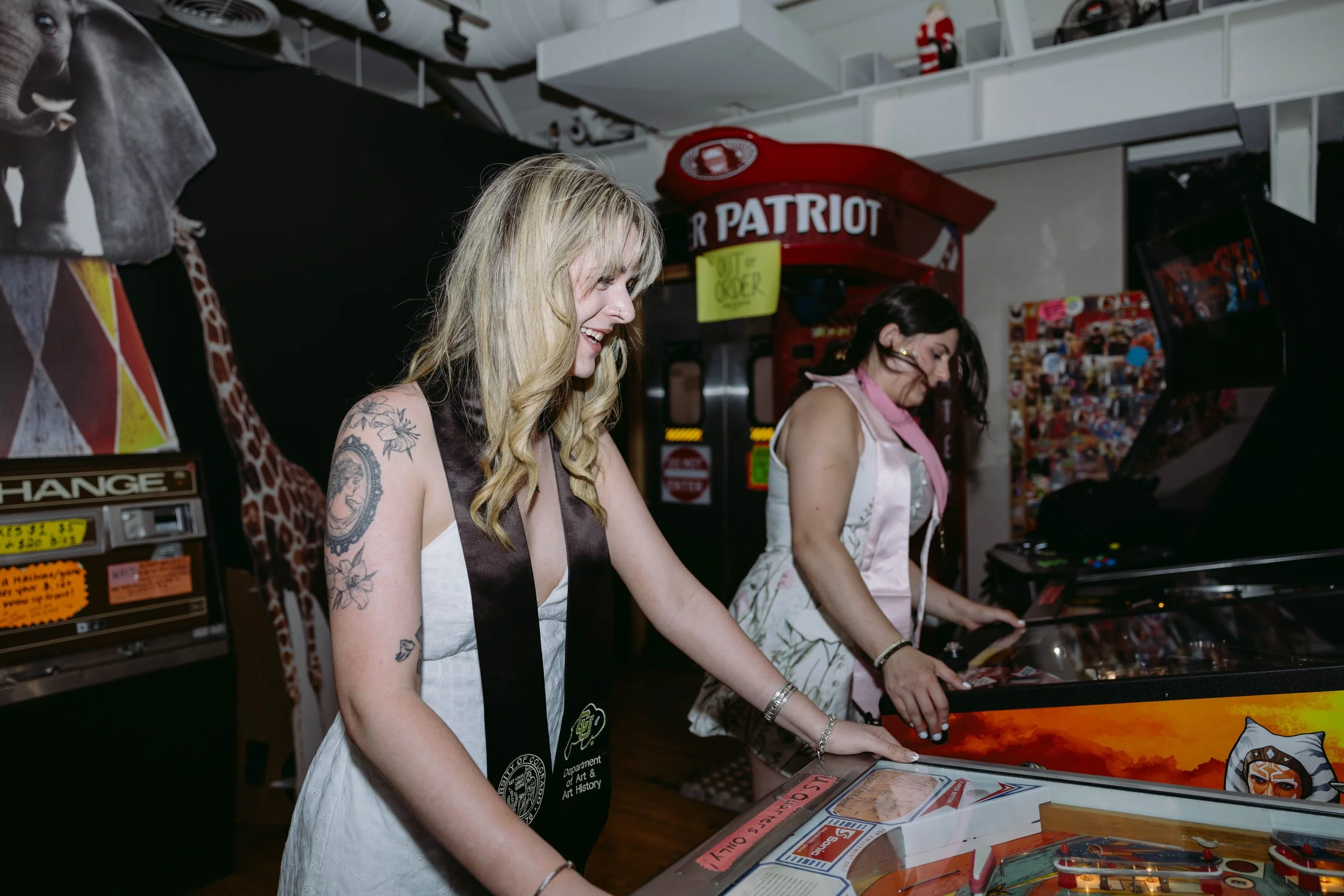 Two girls playing pinball celebrating graduating from the university of Colorado, Boulder