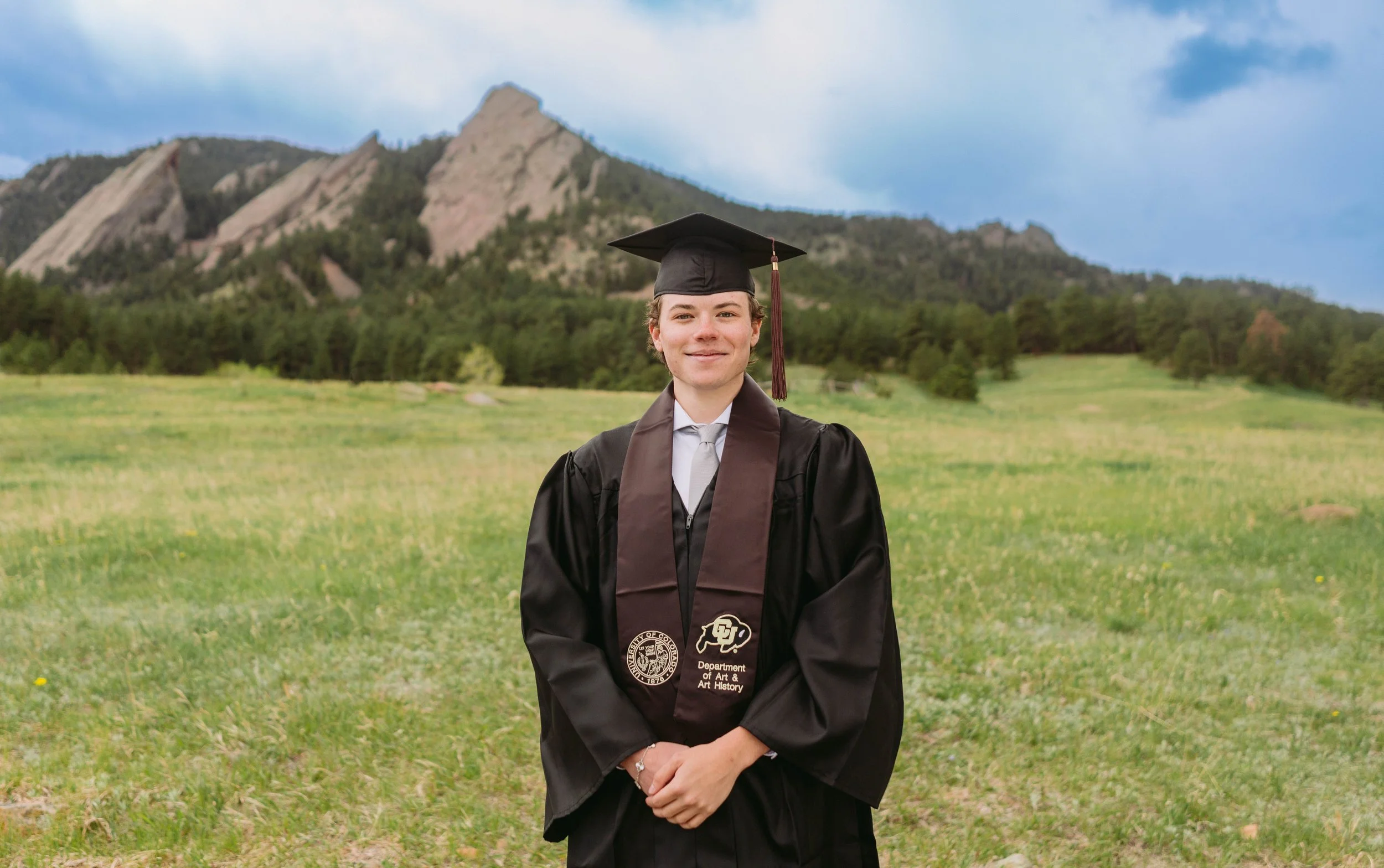 Colorado University, Boulder graduate standing in front of the flatirons at Chautauqua Park