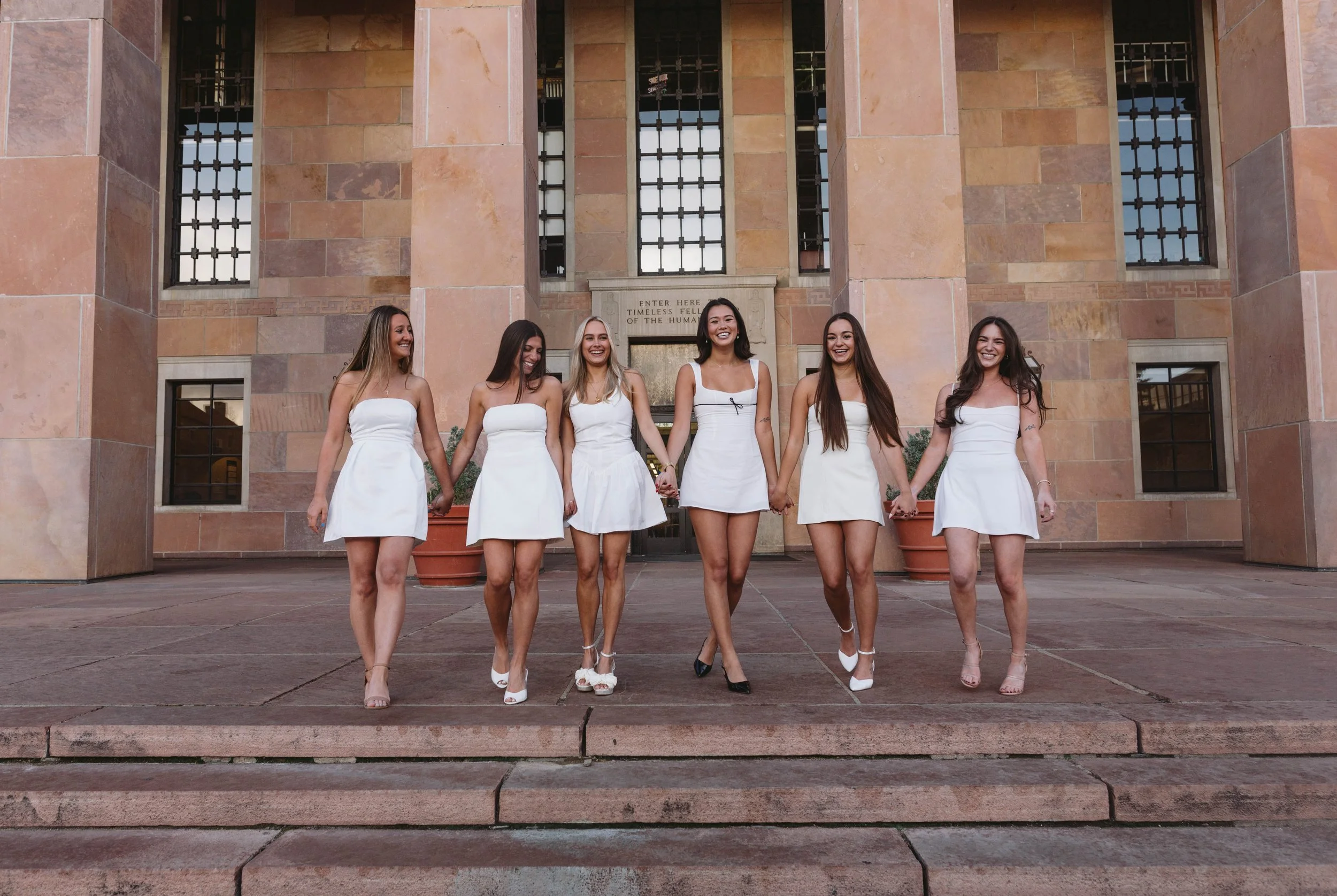 Six girls walking in front of Norlin library holding hands