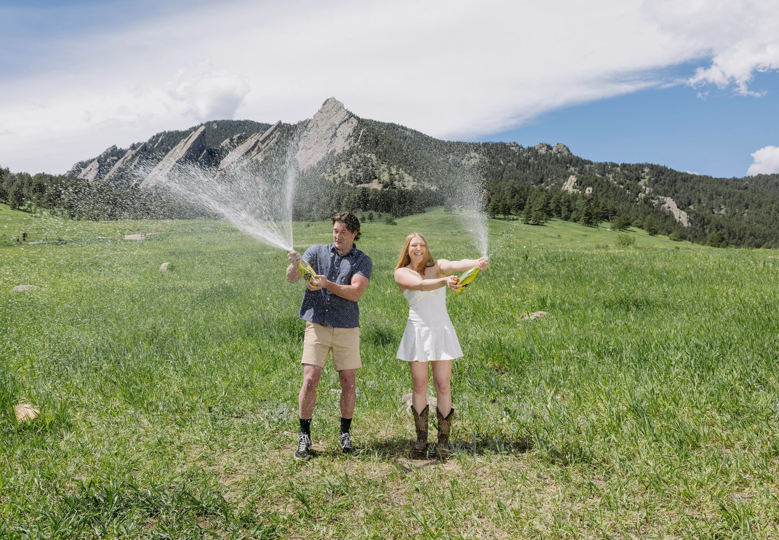 Couple at Chautauqua Park spraying champagne to celebrate graduating from the university of Colorado Boulder