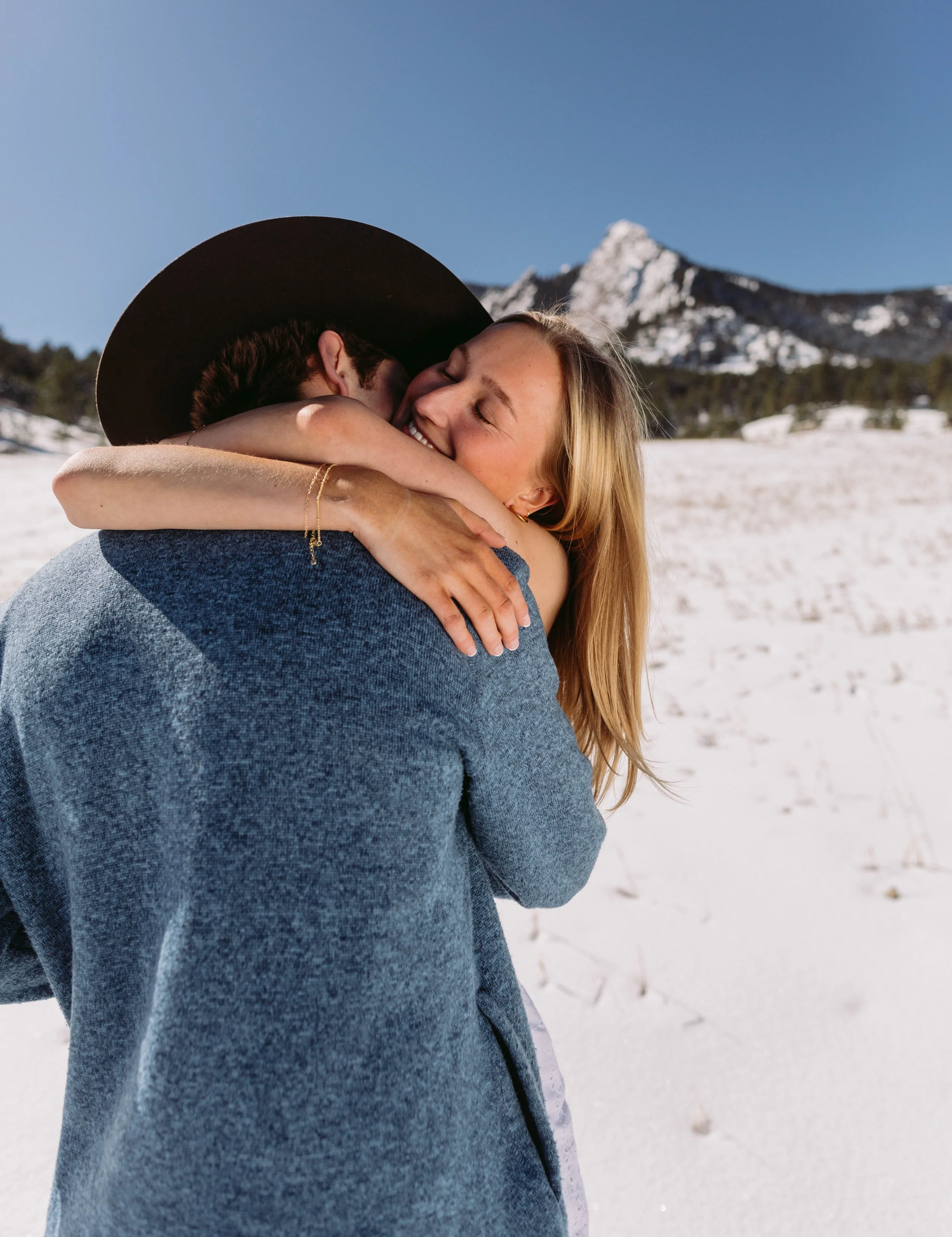 CU Boulder senior couple hugging during winter graduation photos with Flatirons