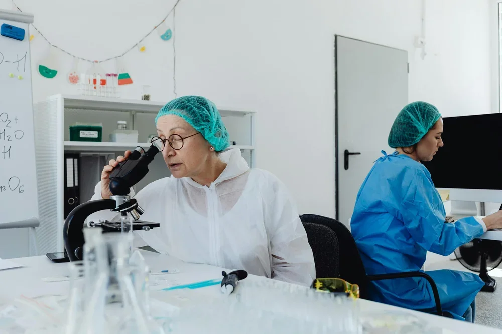 medical professional looking into a microscope for research being conducted by Thay Pharma