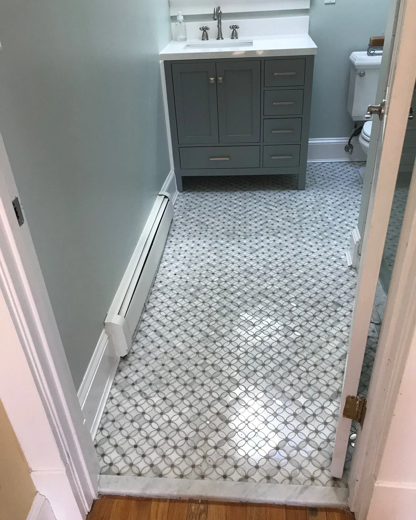New floor in this century home! Mosaic marble tile and a new vanity cabinet. We also spruced up the housing of the hydronic baseboard heater!
