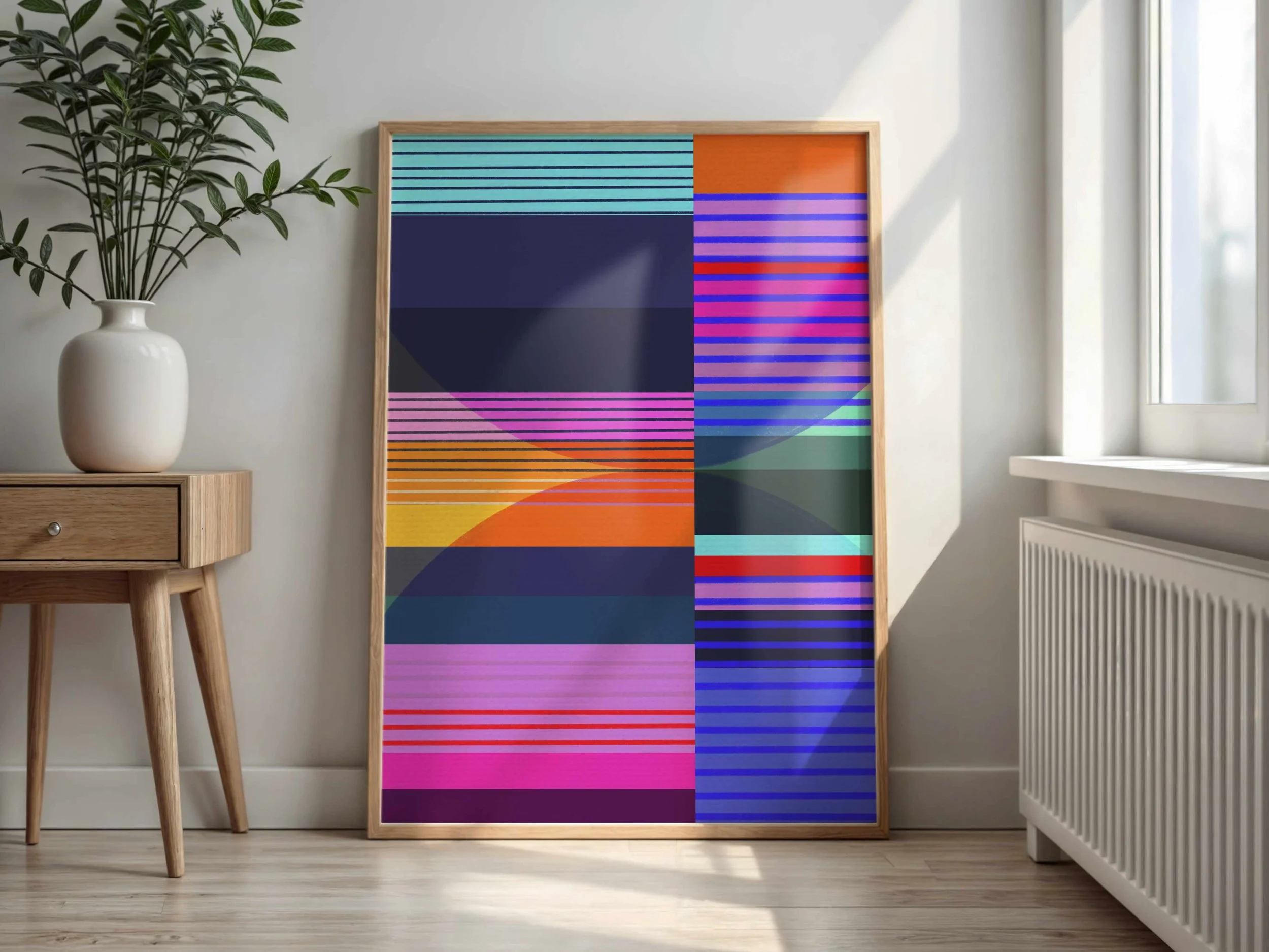 Colorful geometric abstract art with horizontal lines and overlapping circles, in a wooden frame, leaning against a light wall near a window.