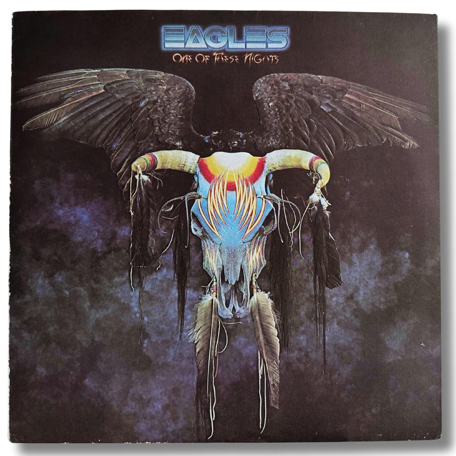 Eagles One of These Nights album cover featuring a painted eagle skull with outstretched wings against a dark cosmic background