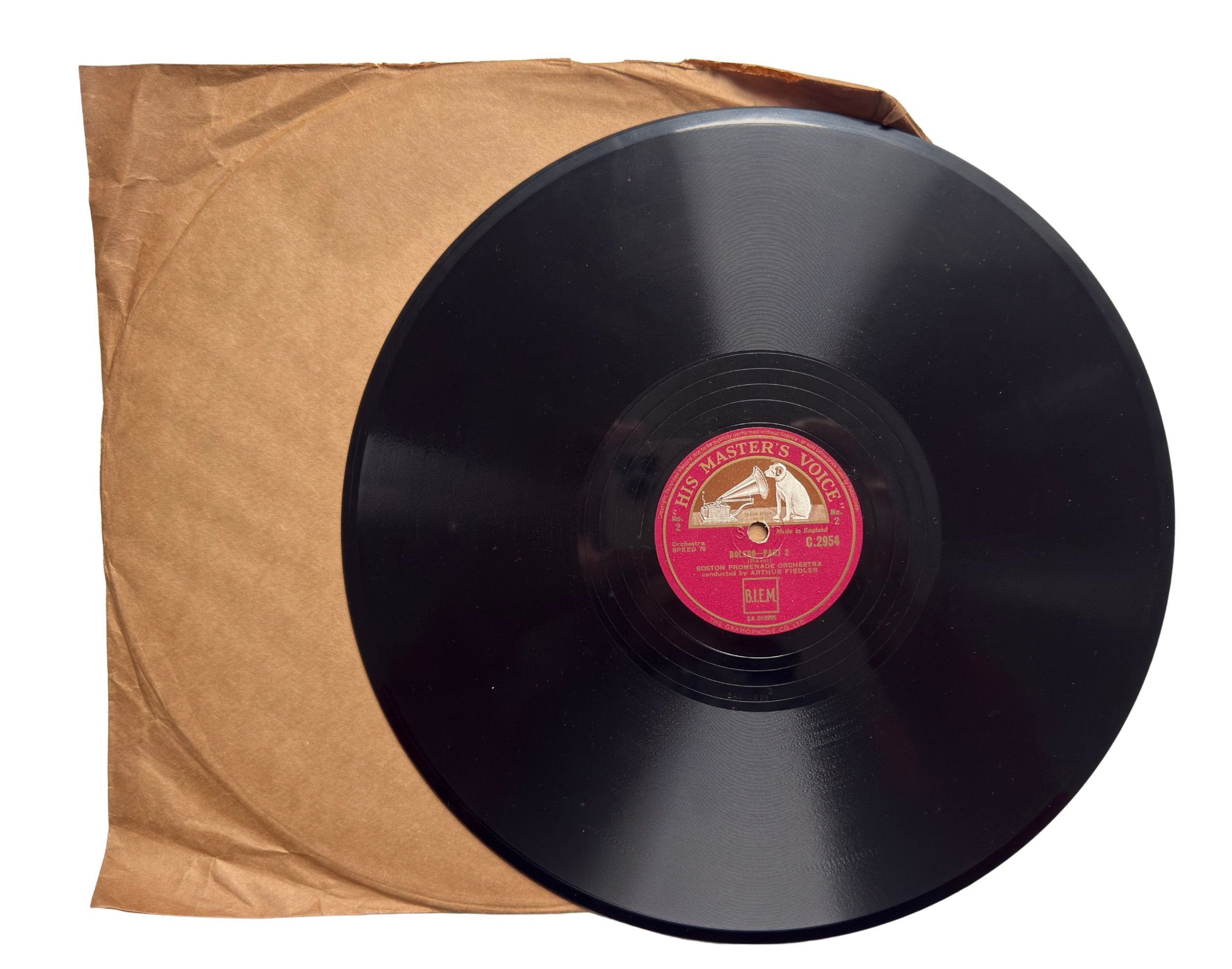 Black shellac 78 rpm record with red HMV label partially removed from a brown paper sleeve.