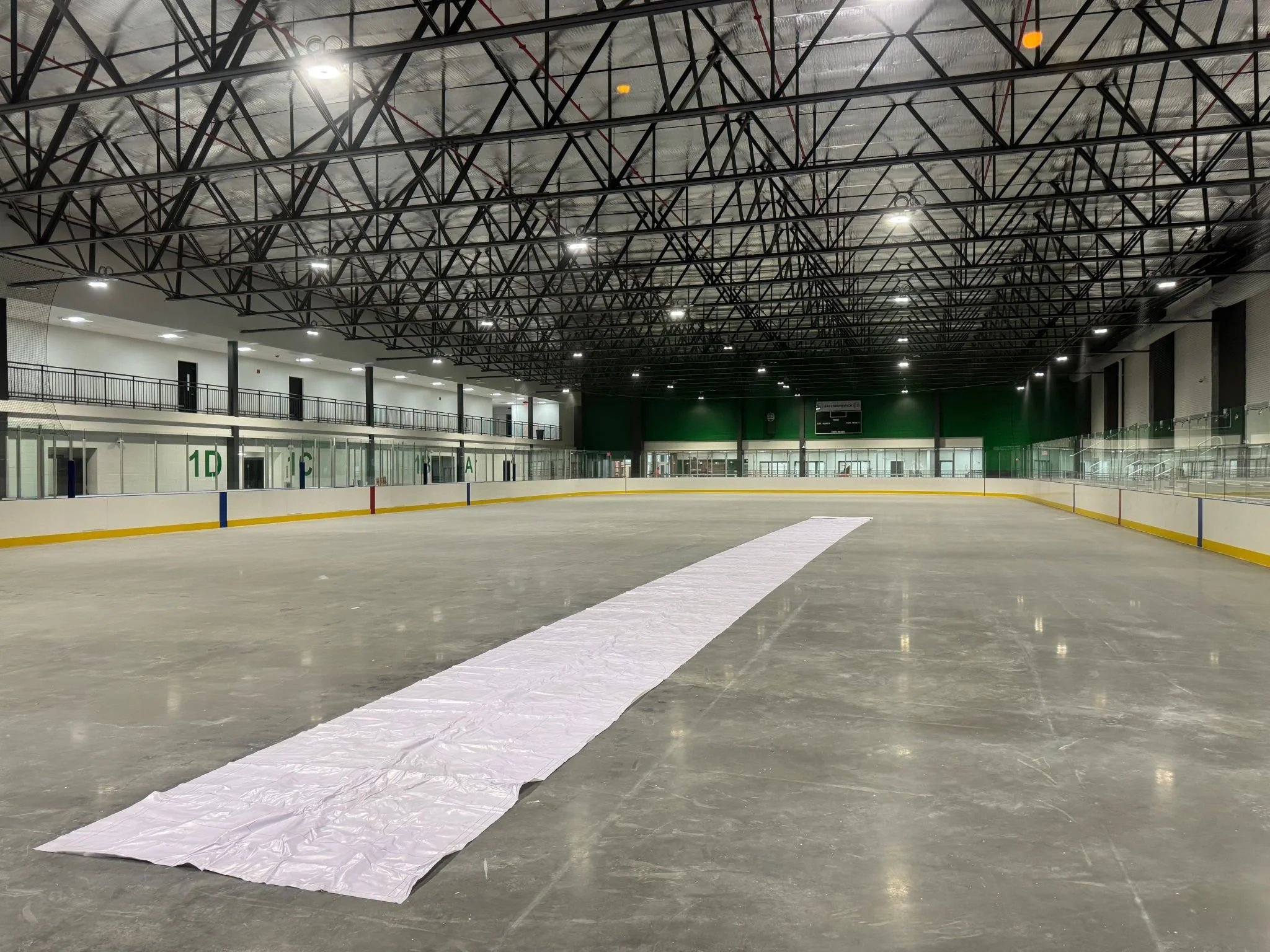 Empty indoor ice hockey rink with a long white cloth on the ice.
